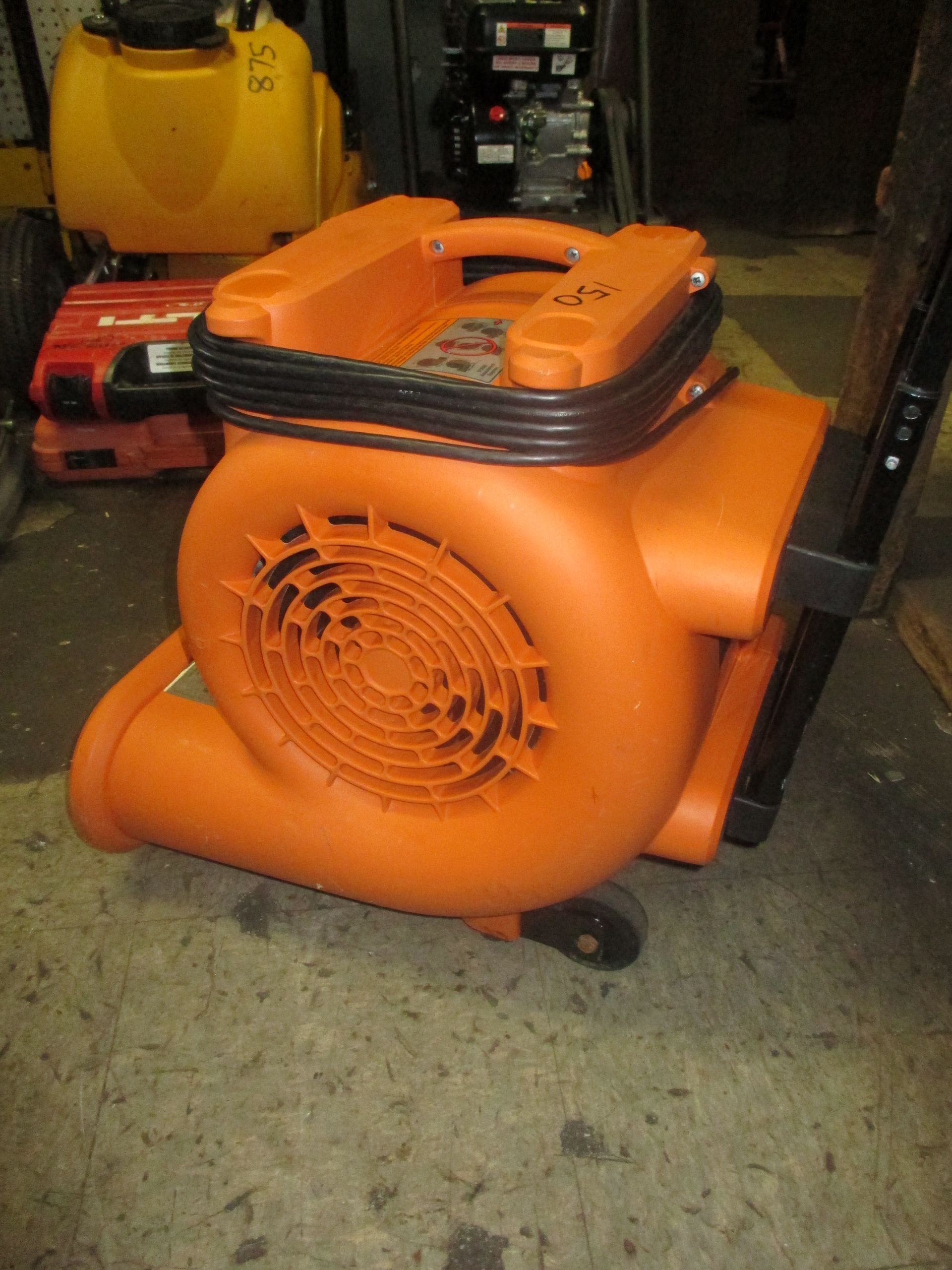 A large orange blower is sitting on a concrete floor.