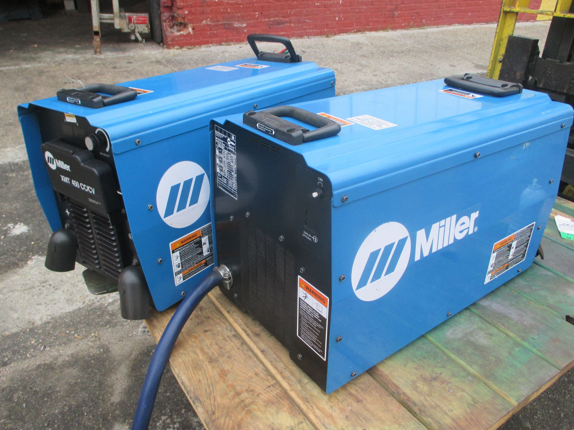 Two miller welding machines are sitting on a wooden table