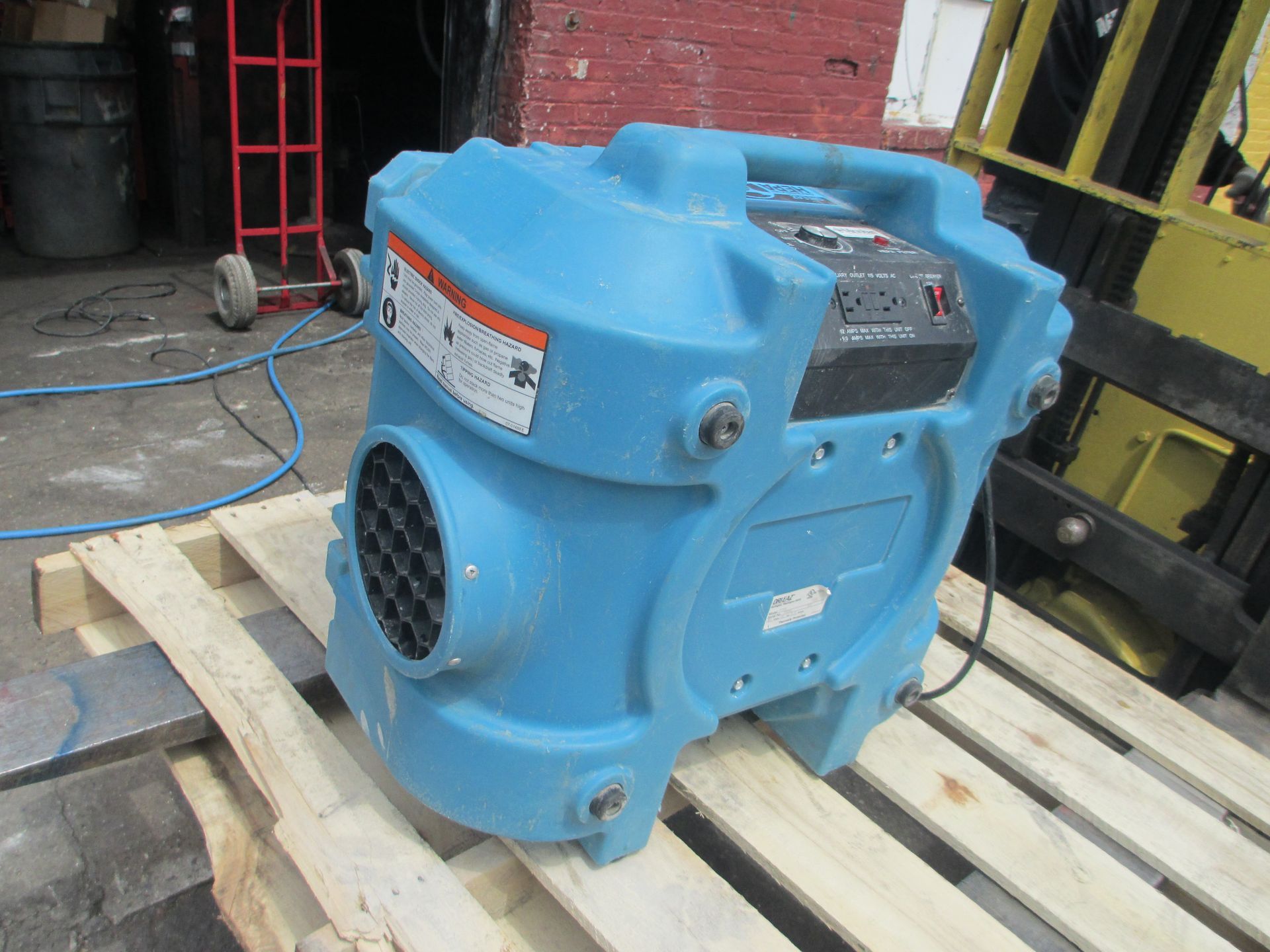 A blue machine is sitting on a wooden pallet