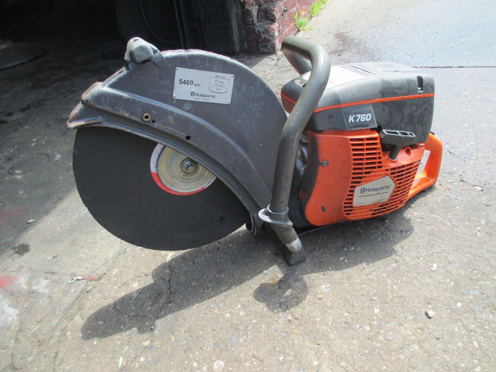 A husqvarna circular saw is sitting on the sidewalk