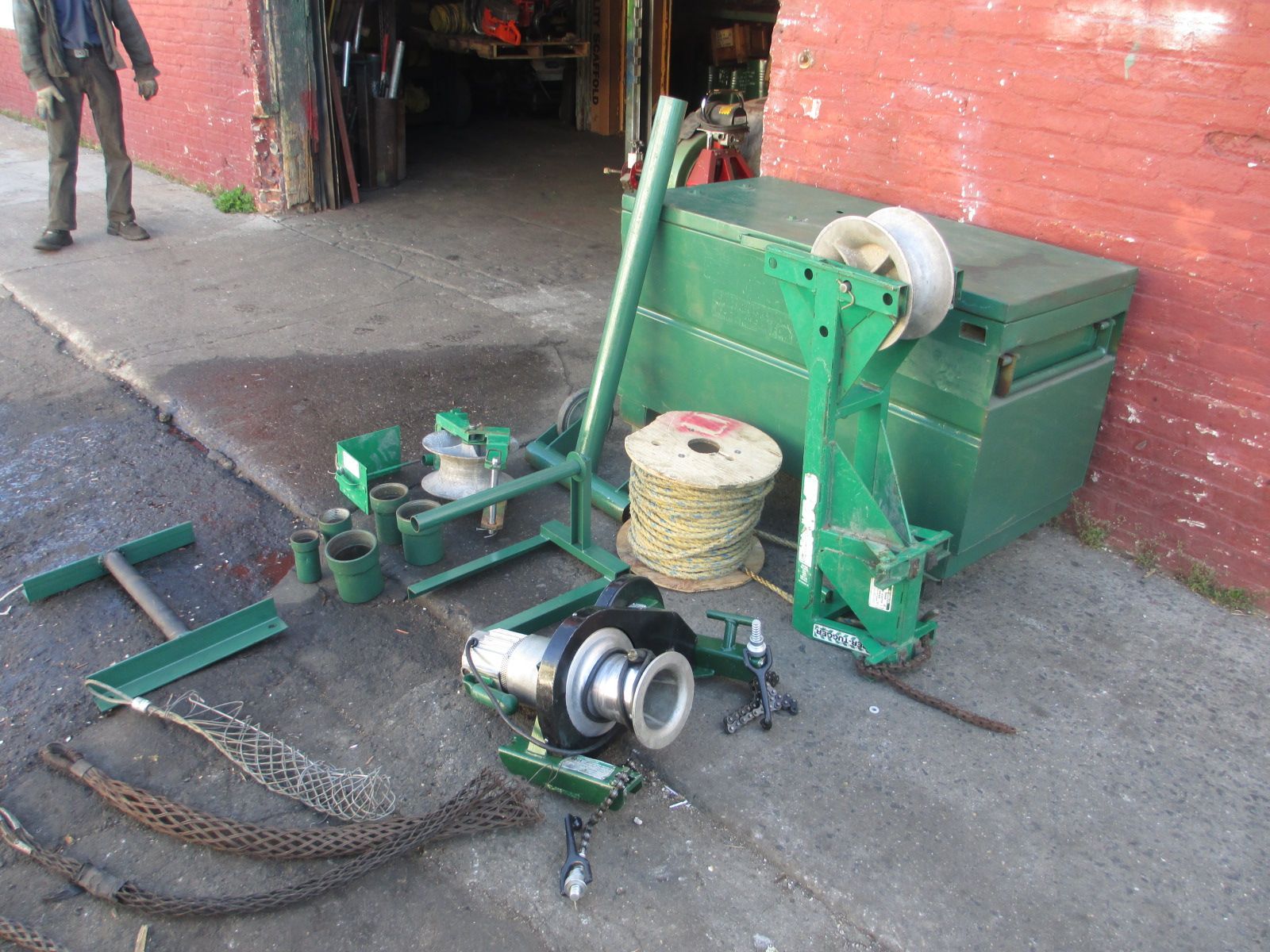 A green machine is sitting on the sidewalk in front of a brick building