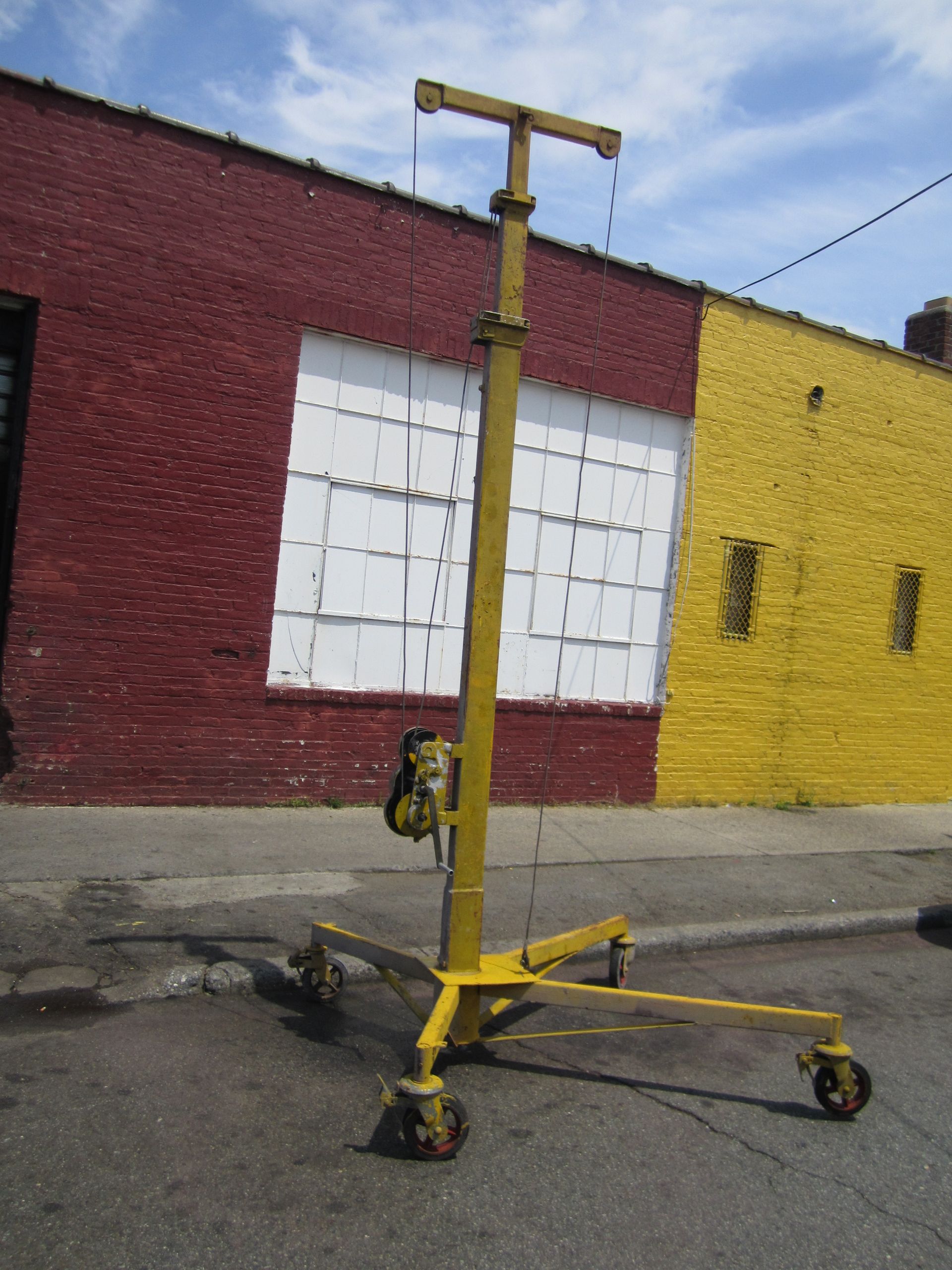 A yellow crane is parked in front of a red and yellow building