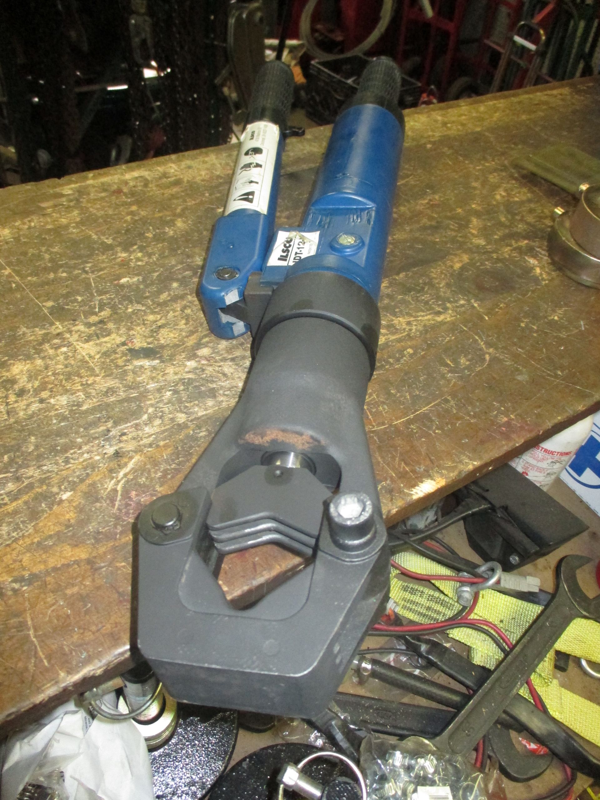 A hydraulic crimping tool is sitting on a wooden table