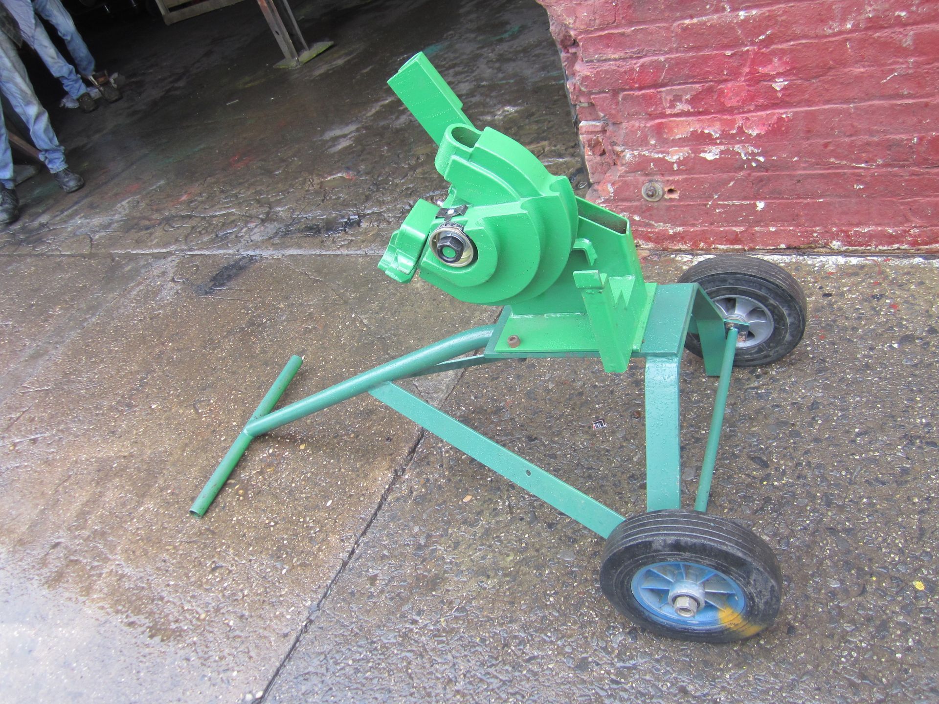 A green machine with wheels is sitting on the ground