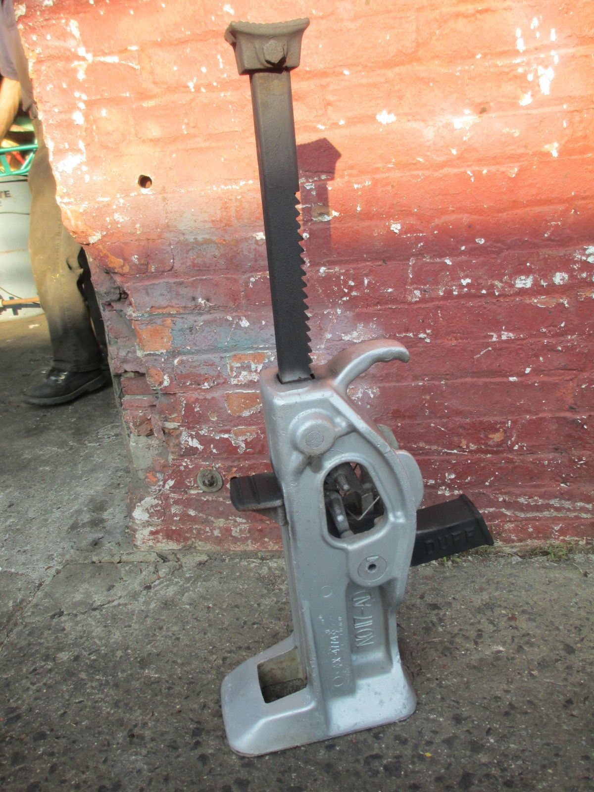 A car jack is sitting in front of a red brick wall