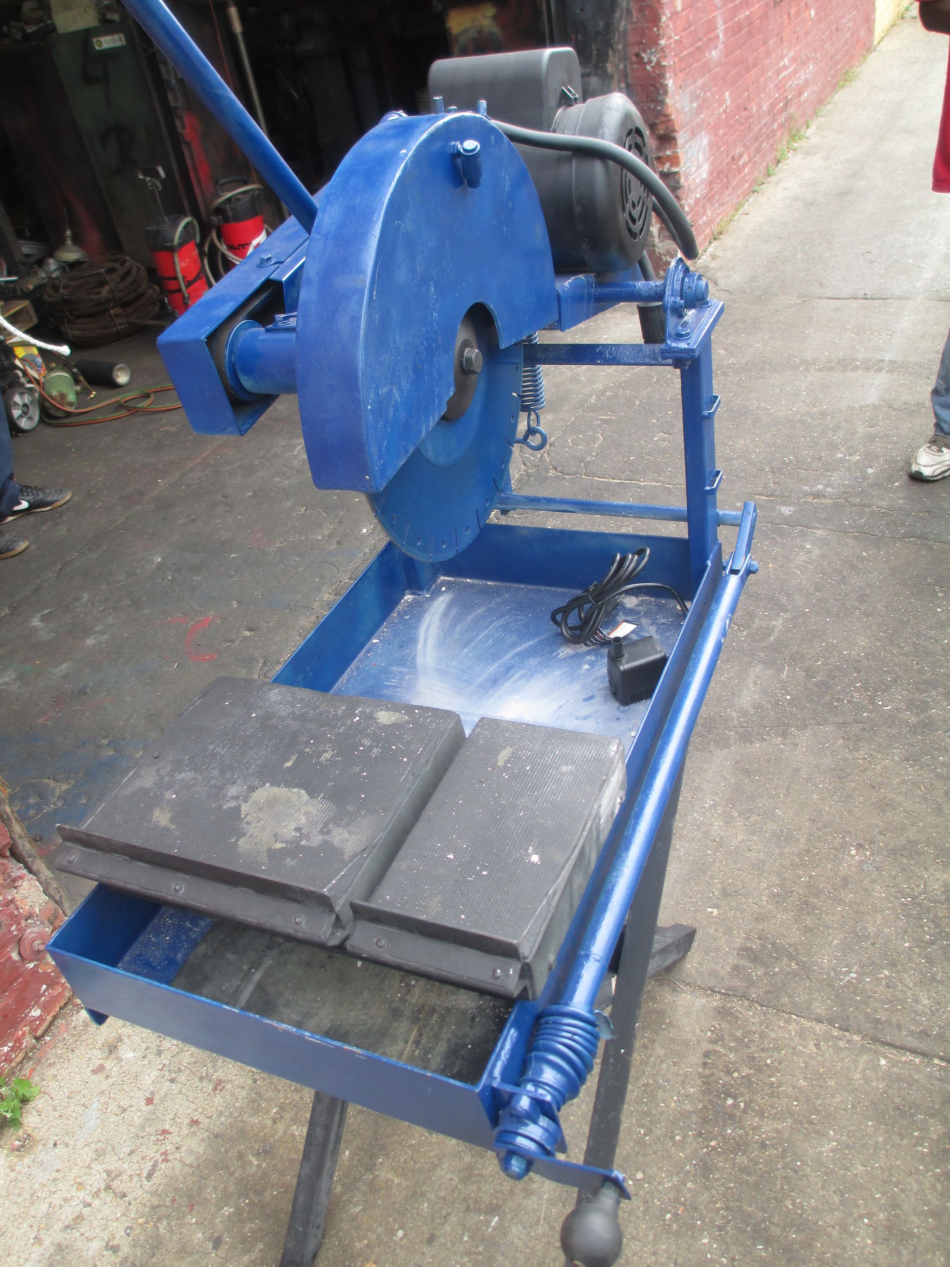 A blue machine with a motor is sitting on the sidewalk