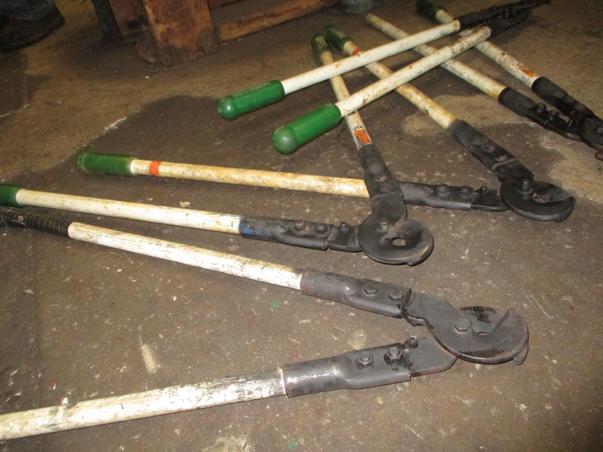 A bunch of tools with green handles are laying on the ground