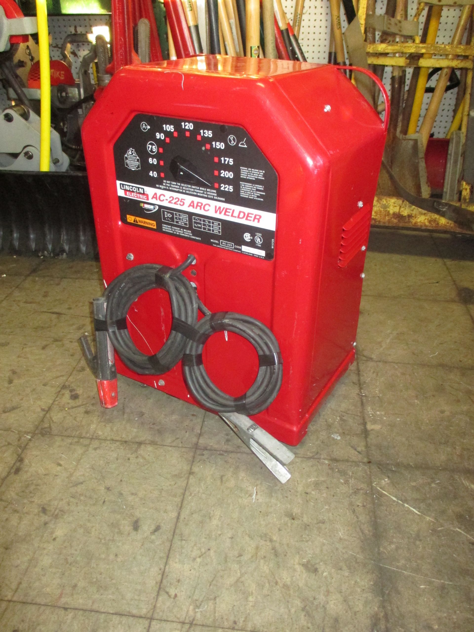 A red welding machine is sitting on a tiled floor