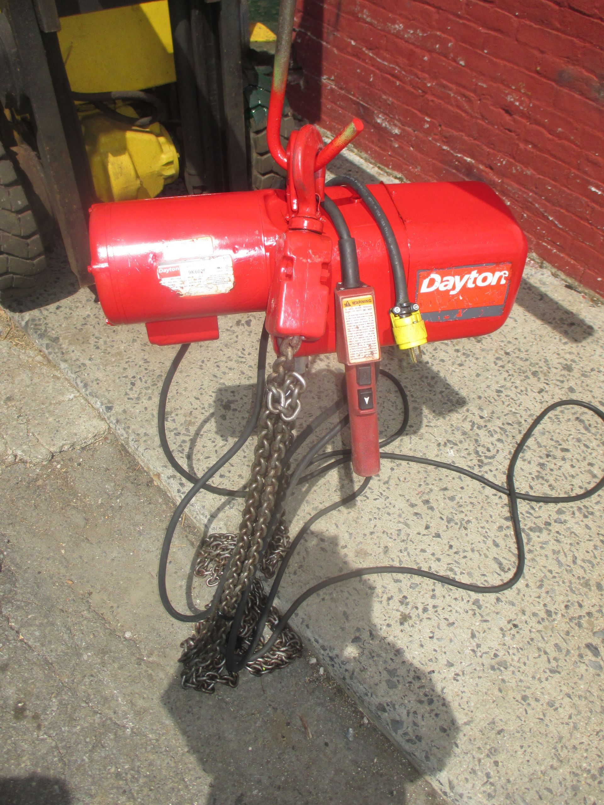 A red dayton chain hoist is attached to a forklift