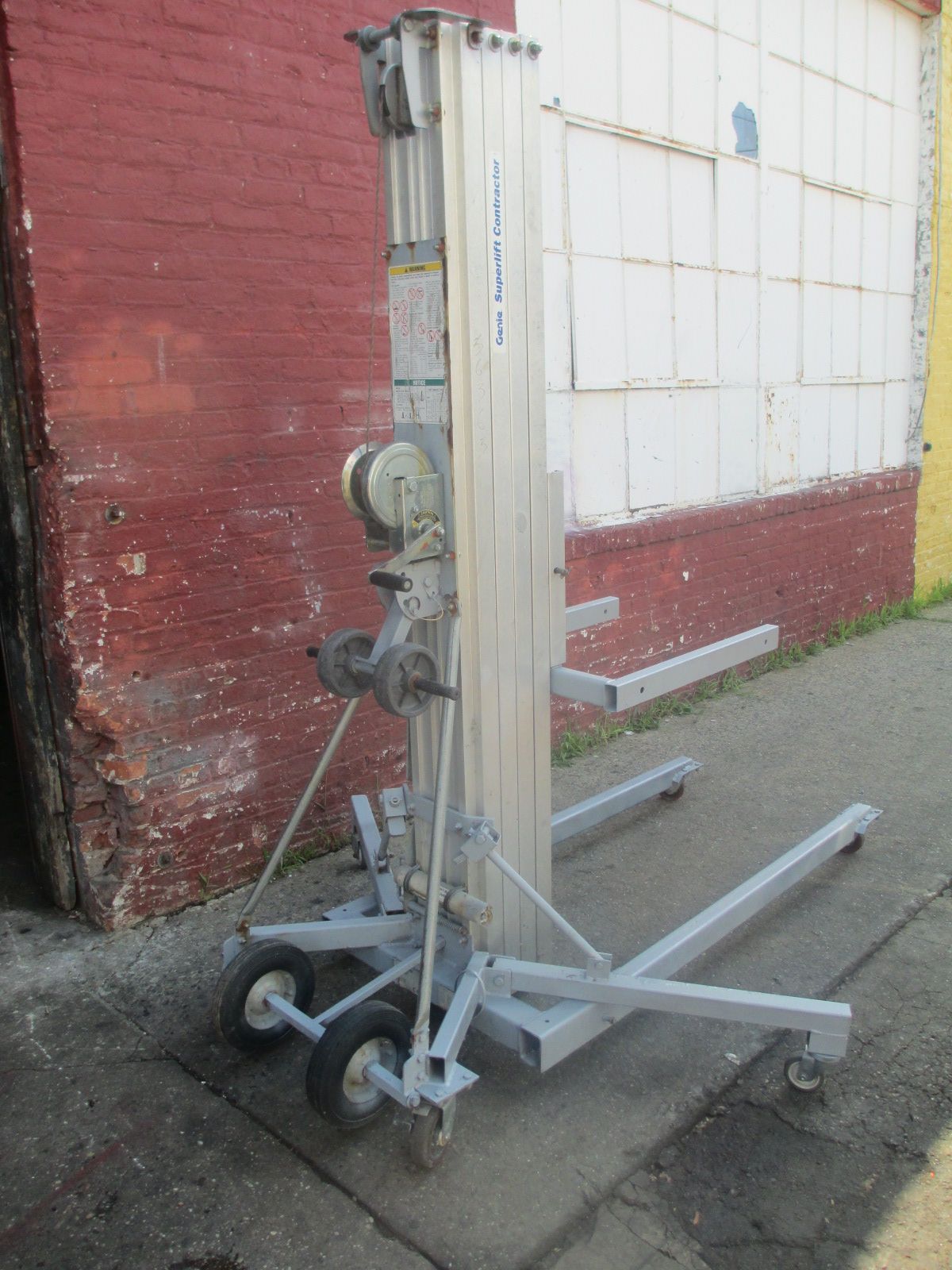 A very tall machine is sitting on the sidewalk in front of a brick building
