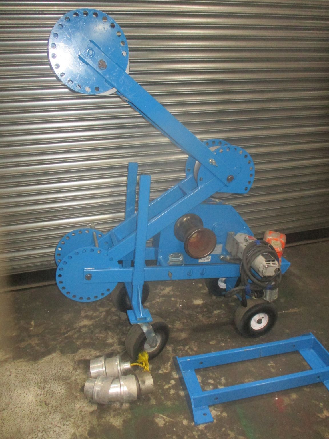 A blue machine with wheels is sitting on a concrete floor.