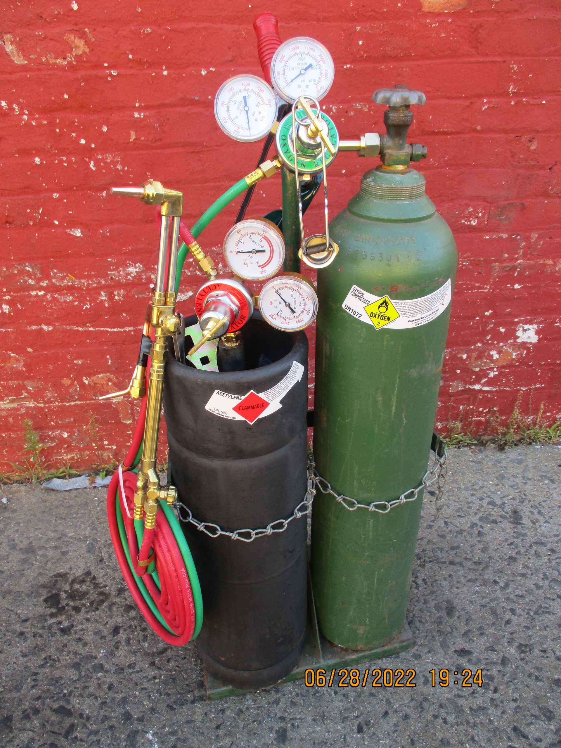 Two gas cylinders are sitting next to each other in front of a red brick wall