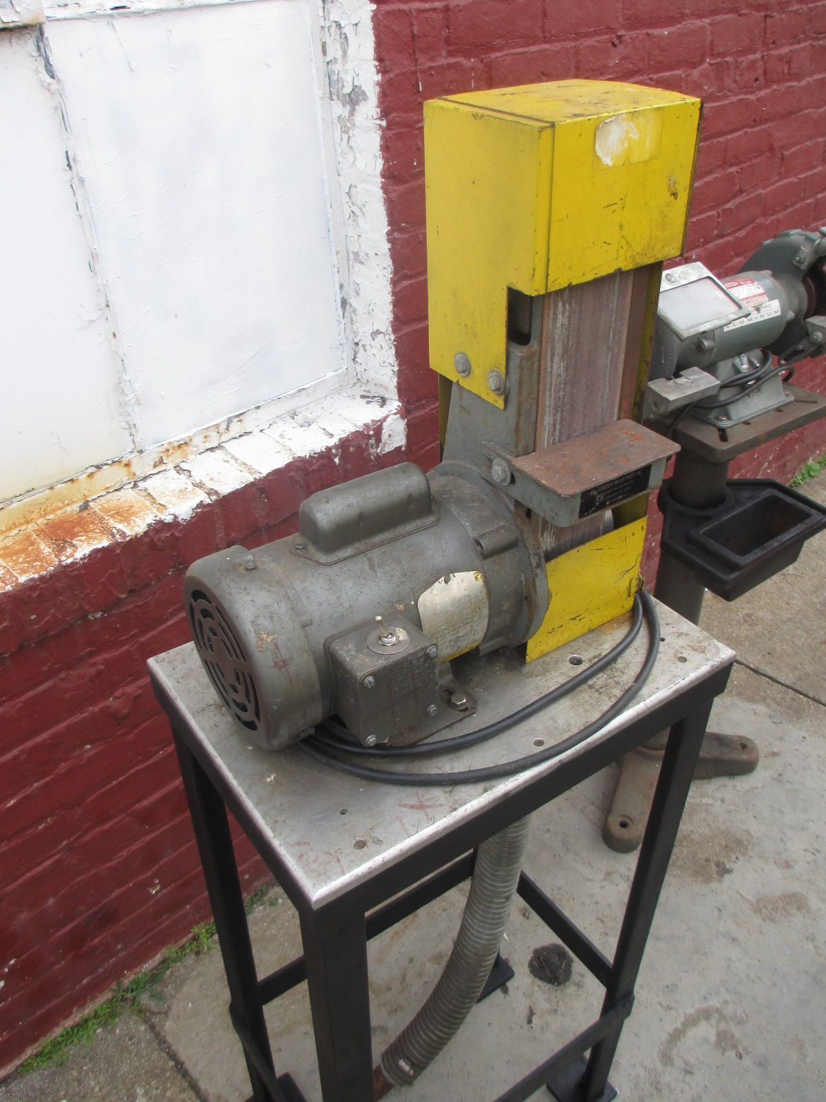 A machine is sitting on a small table in front of a brick wall