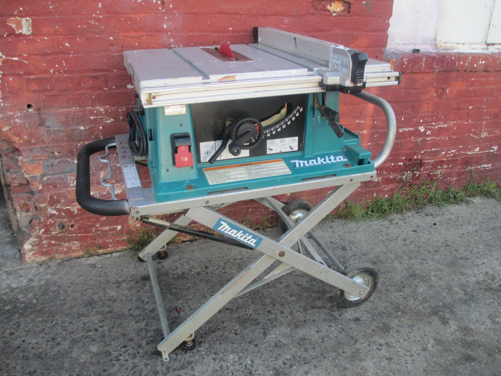 A makita table saw is sitting in front of a brick wall