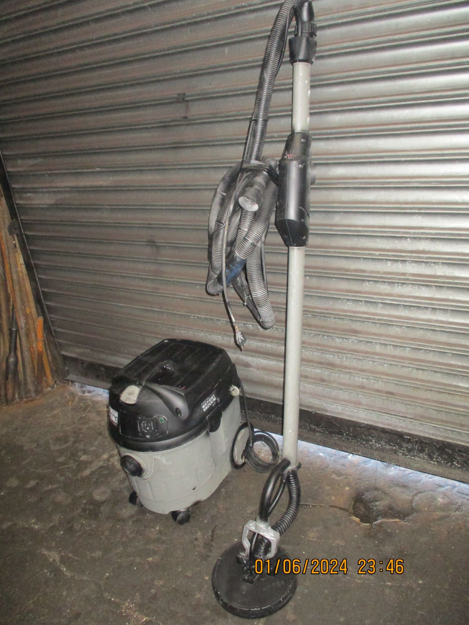 A vacuum cleaner is sitting in front of a garage door.