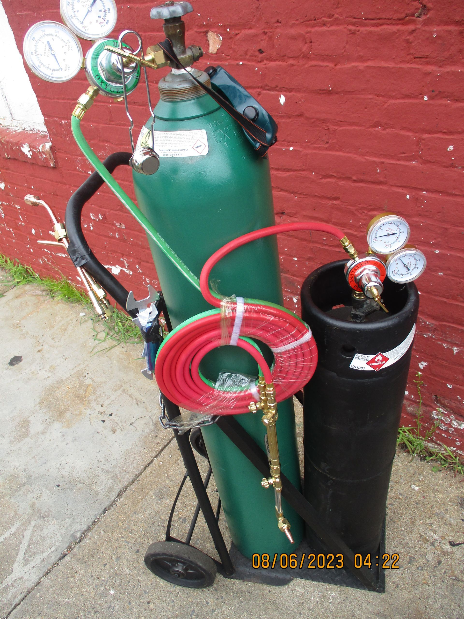A green cylinder with a red hose attached to it