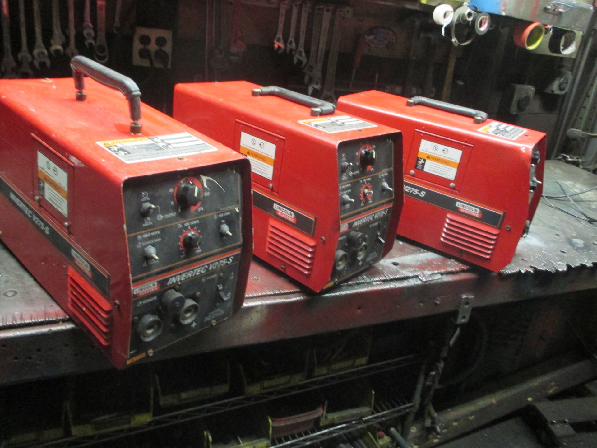 Three red welding machines are sitting on a table
