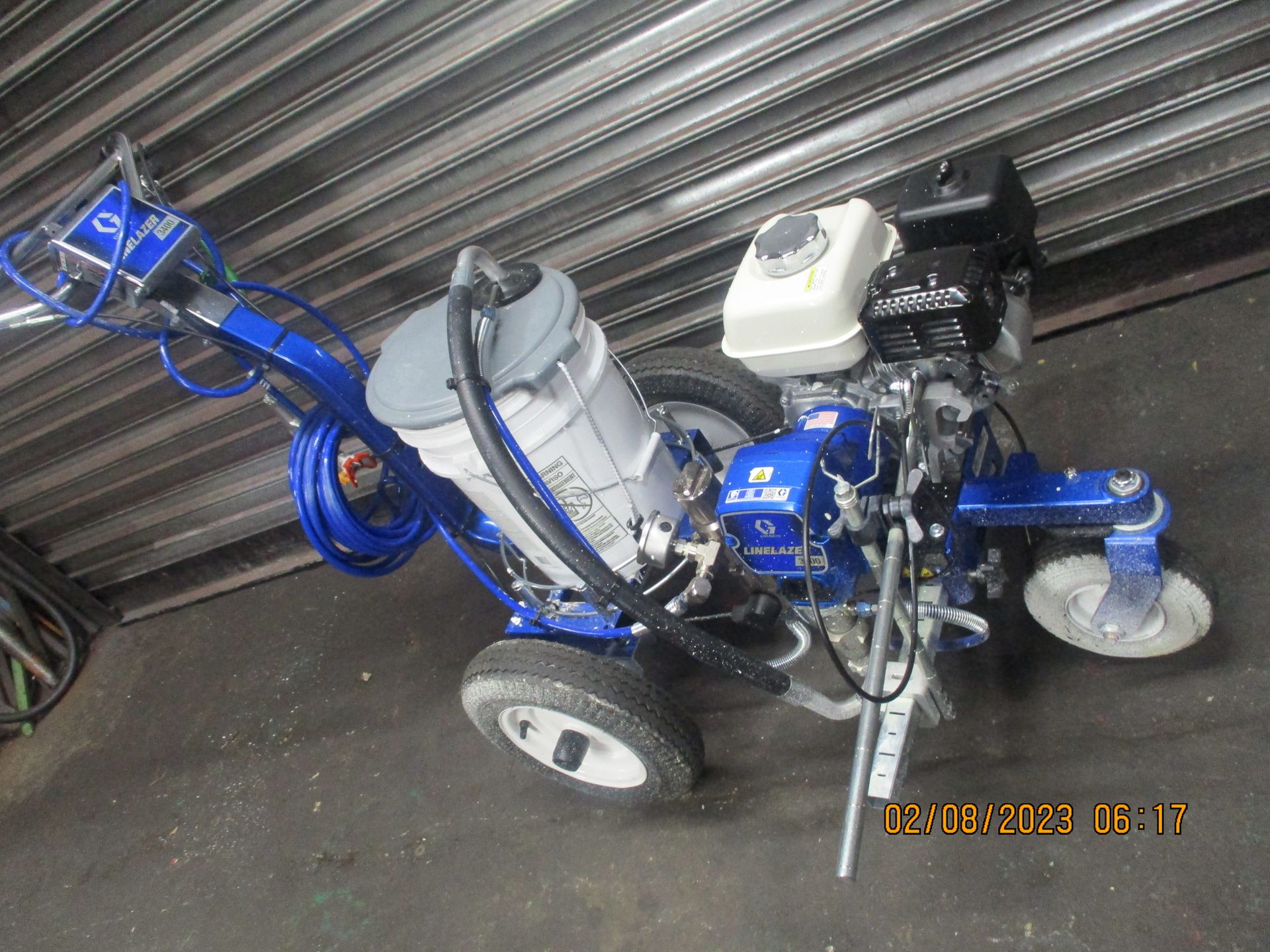 A blue and gray machine is sitting in front of a garage door.