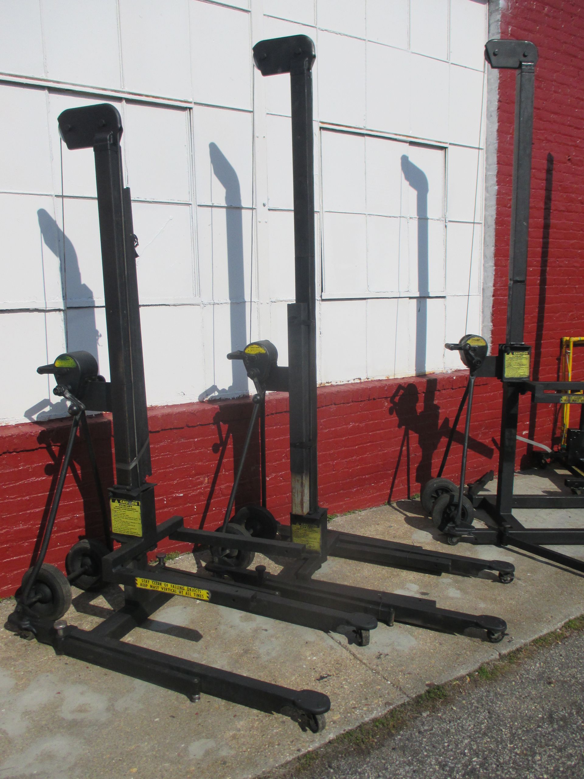 A row of forklifts are lined up in front of a red brick building