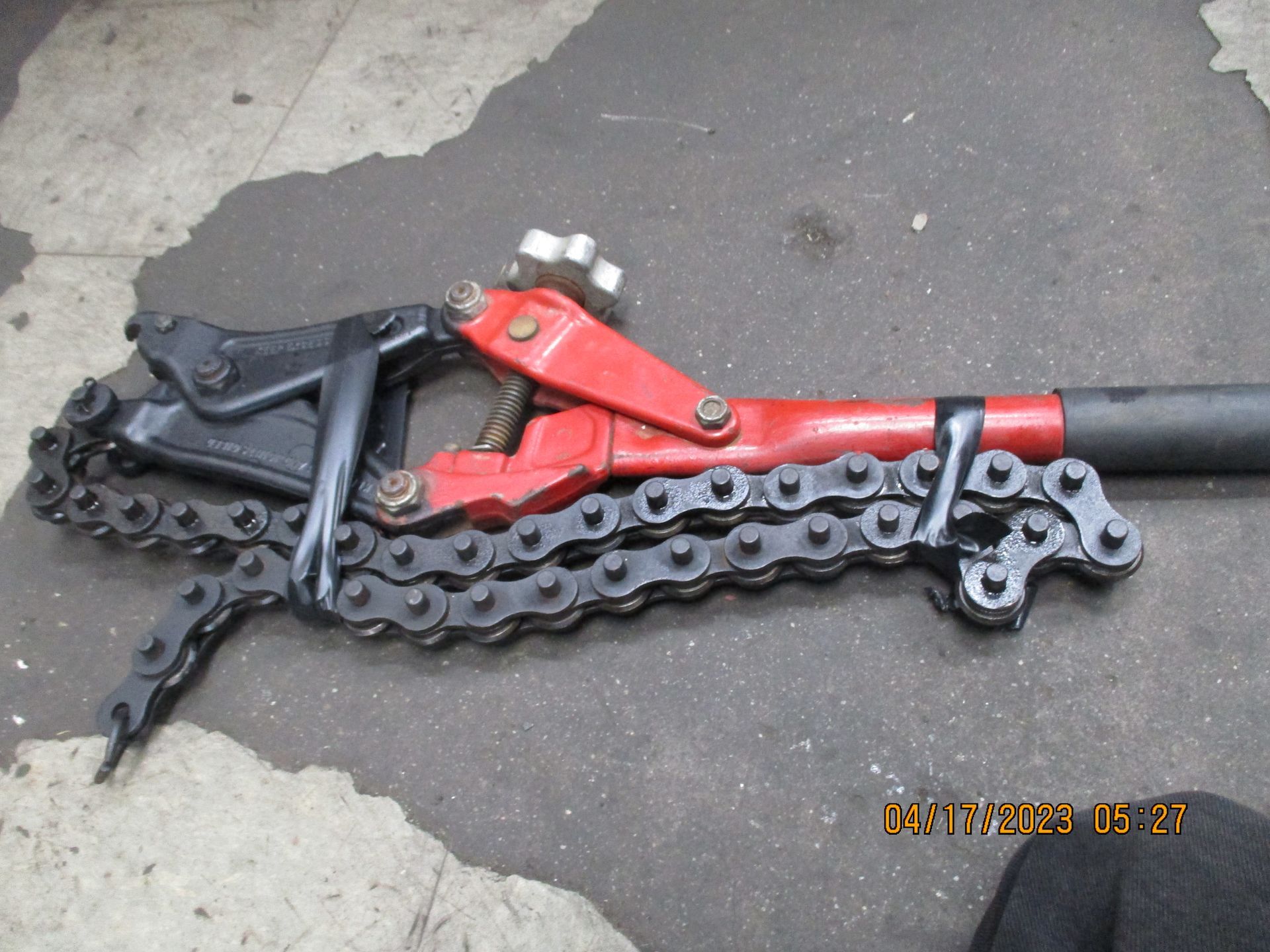 A red and black tool with a chain attached to it