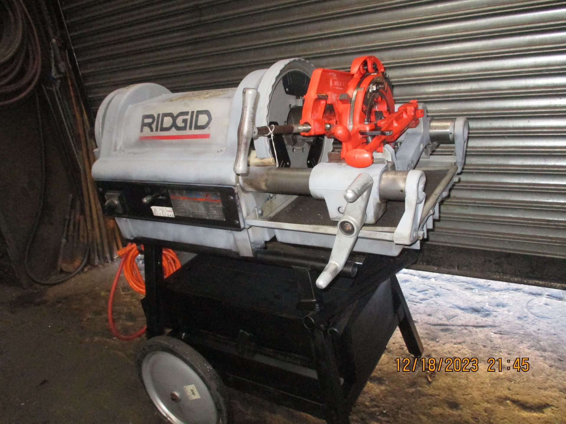 A ridgid machine is sitting on a cart in front of a garage door.