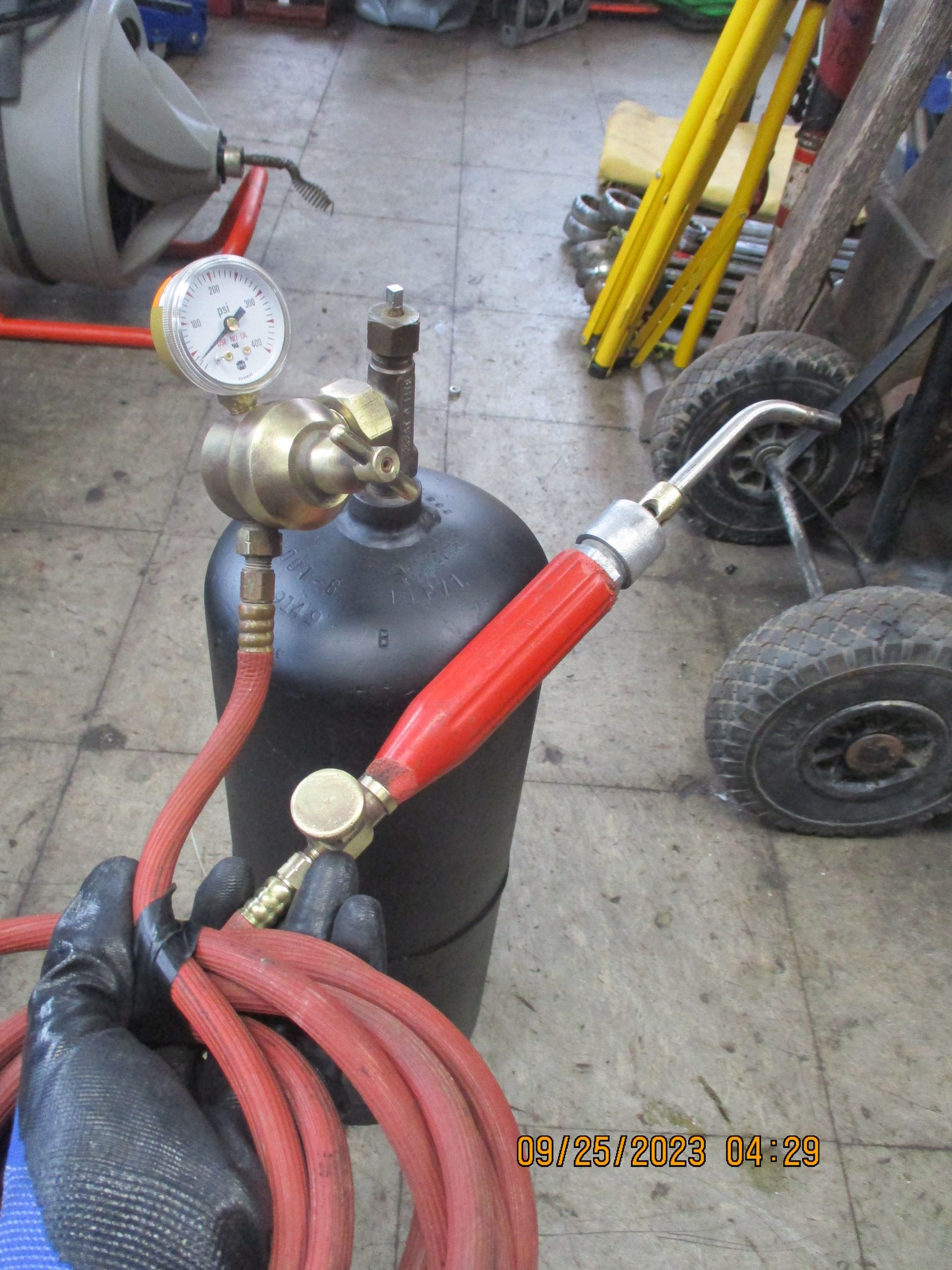 A person is holding a welding torch with a red handle