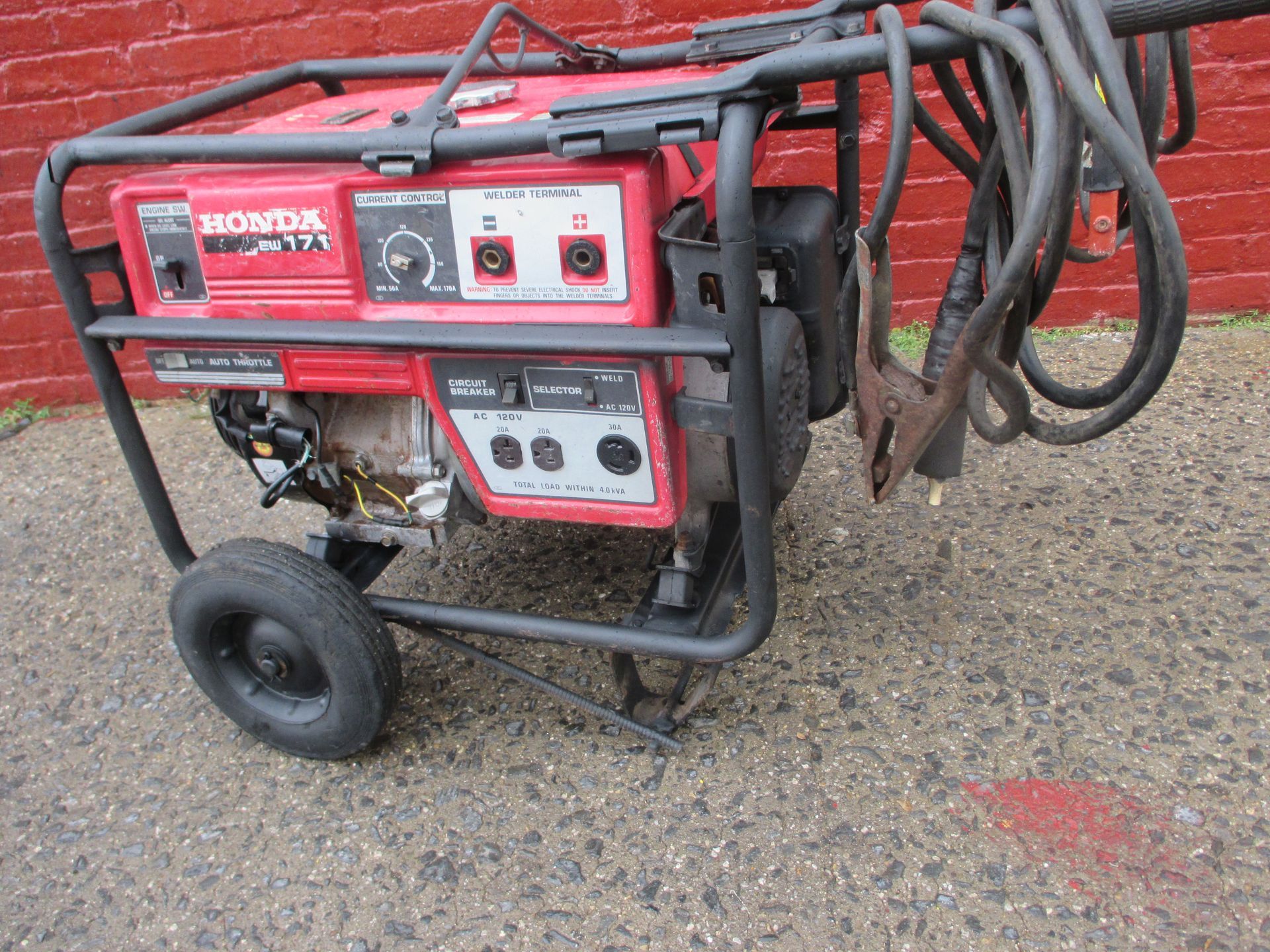 A red honda generator is sitting on the ground