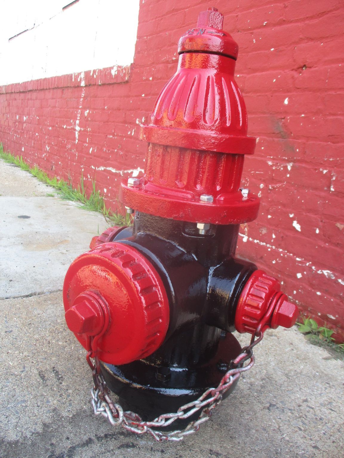 A red and black fire hydrant with a chain attached to it