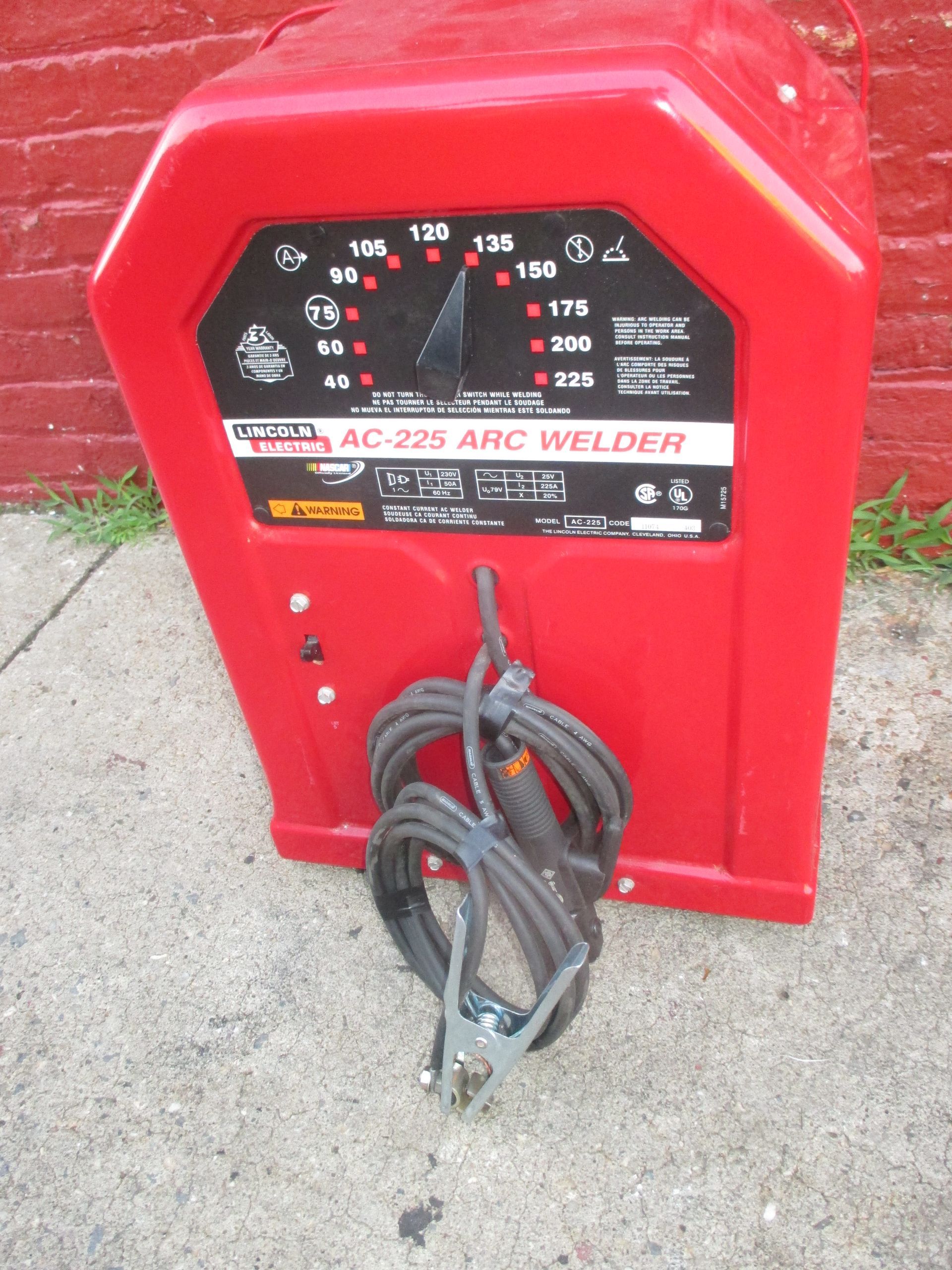 A lincoln brand welding machine is sitting on the sidewalk