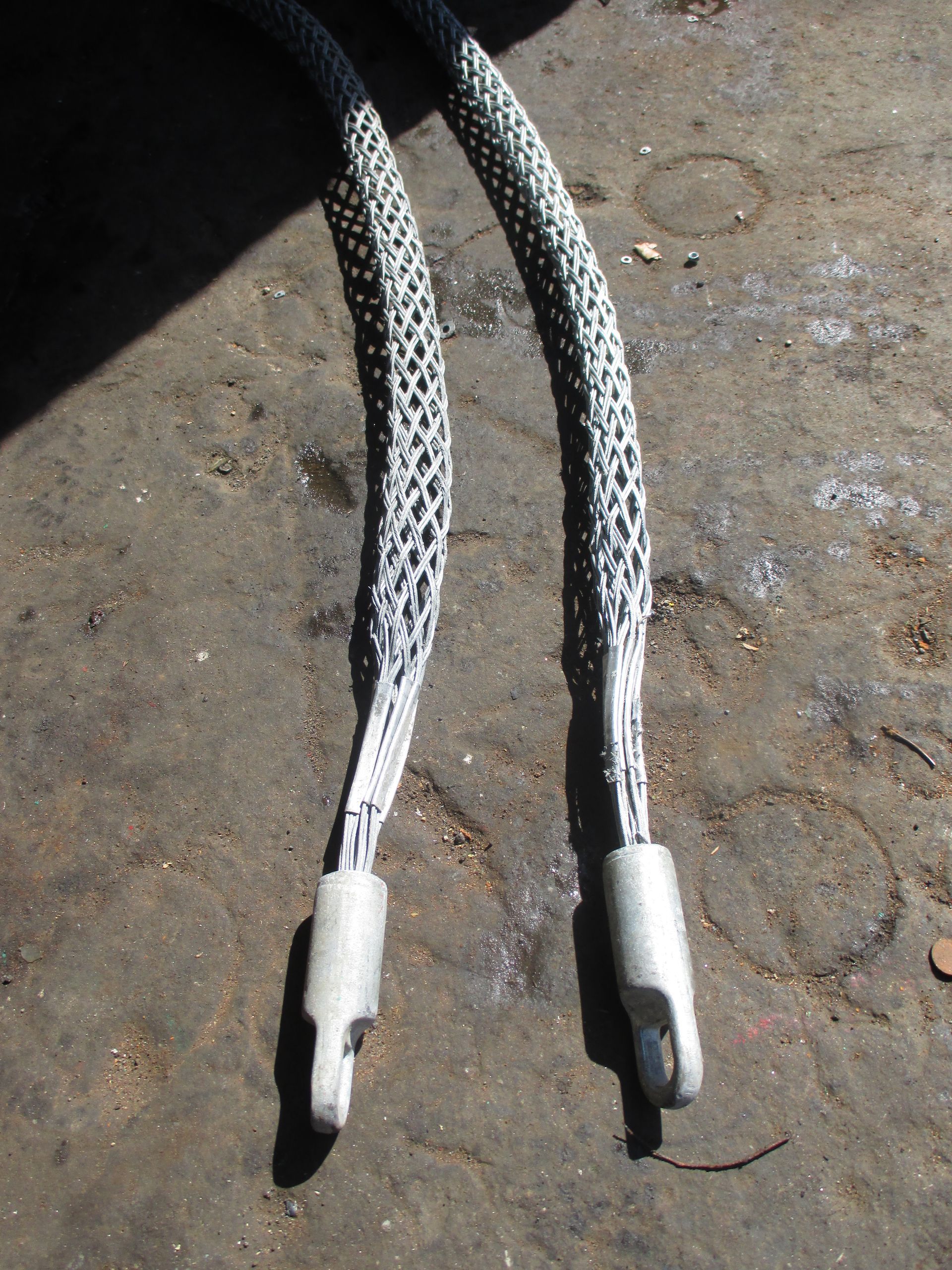 A pair of ropes with metal ends are laying on the ground