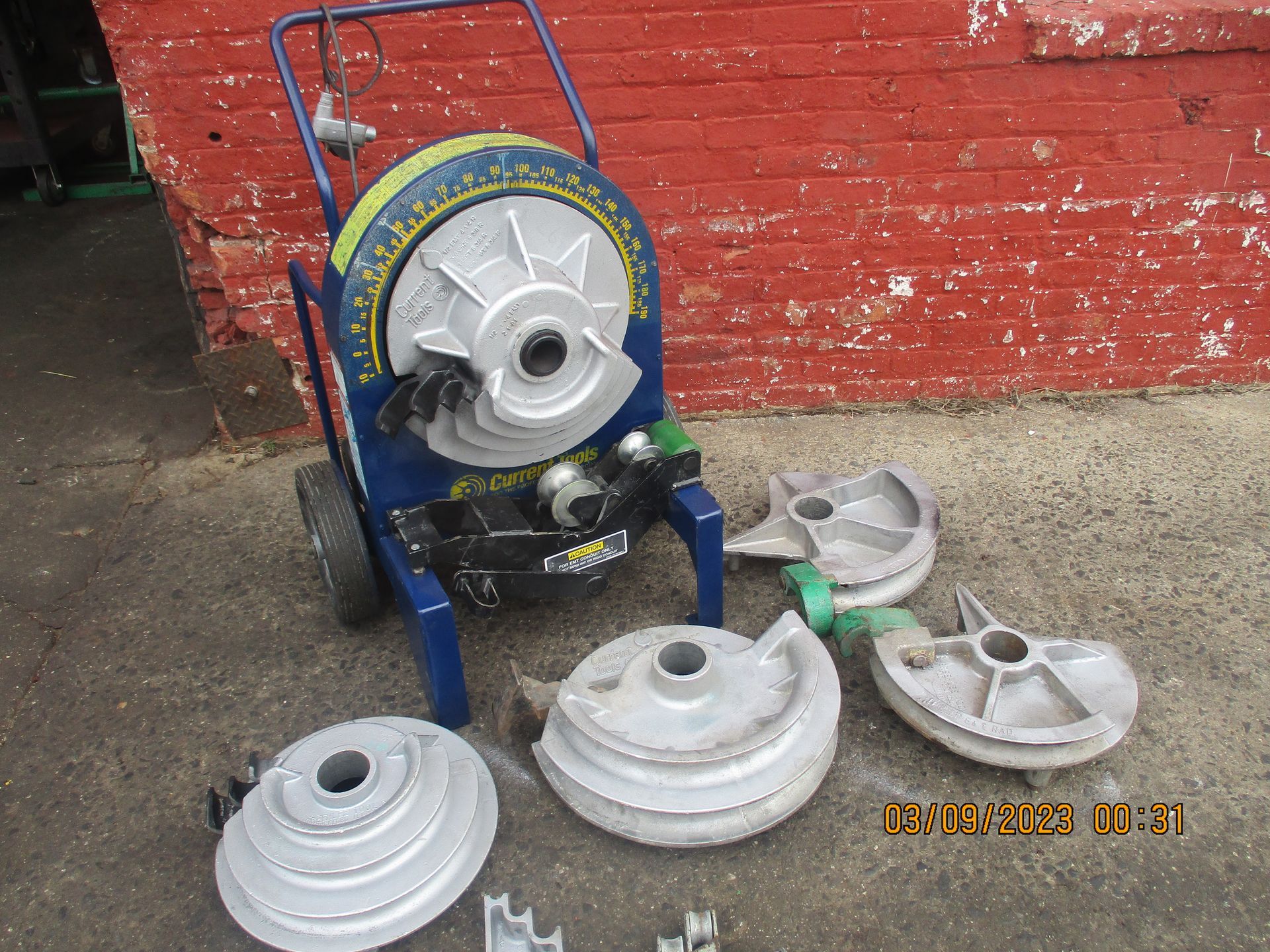 A machine is sitting in front of a red brick wall.