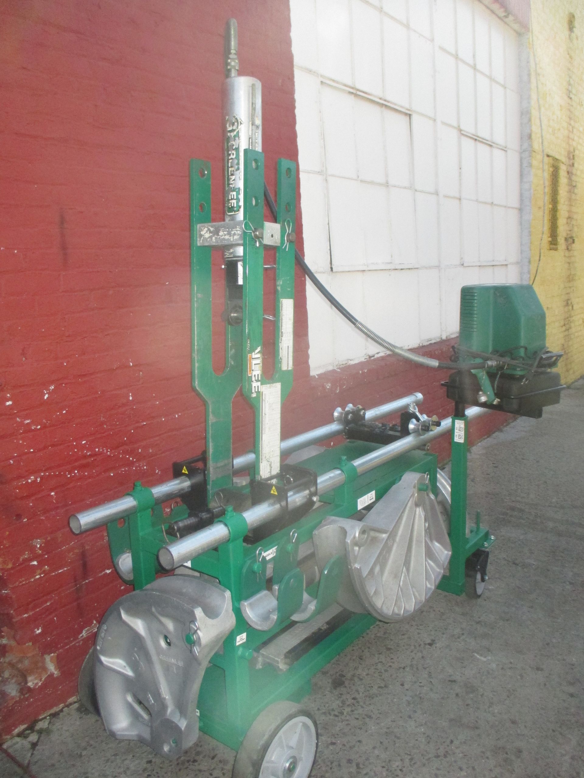 A green machine is parked in front of a red wall