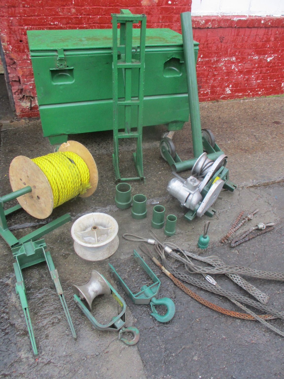 A bunch of tools are sitting on the ground in front of a green box
