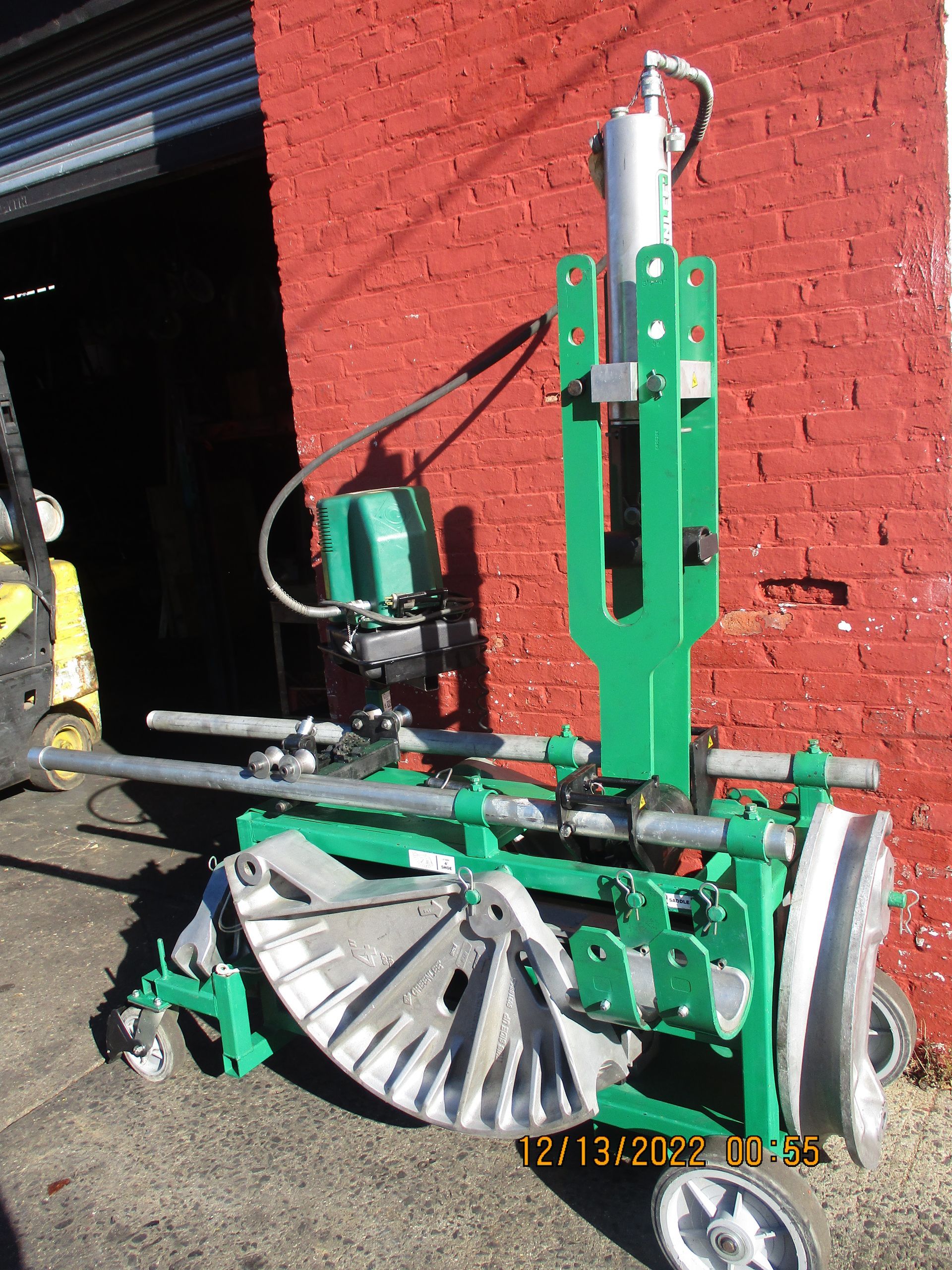 A green machine is sitting in front of a red brick wall