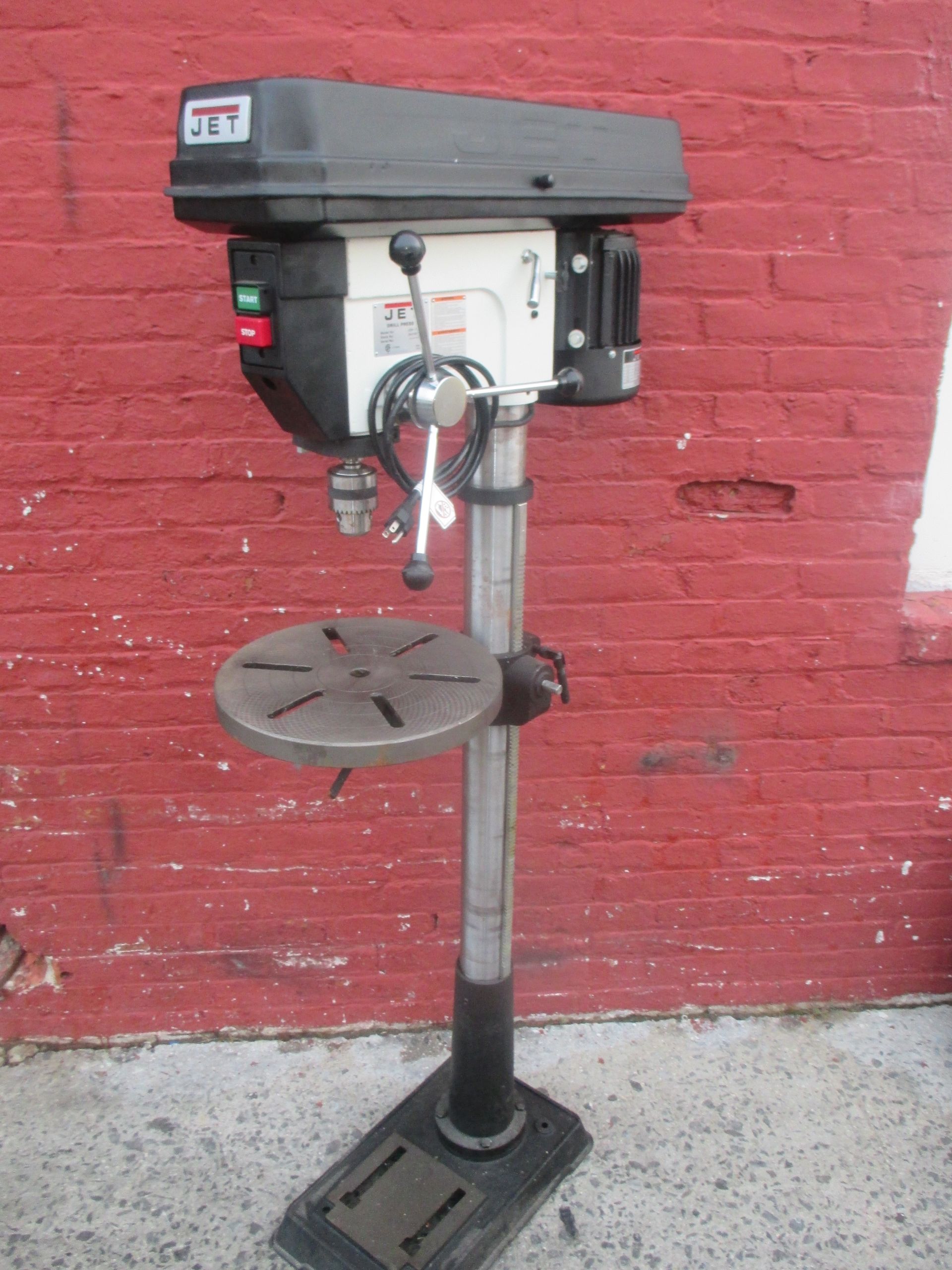 A jet drill is sitting in front of a red brick wall