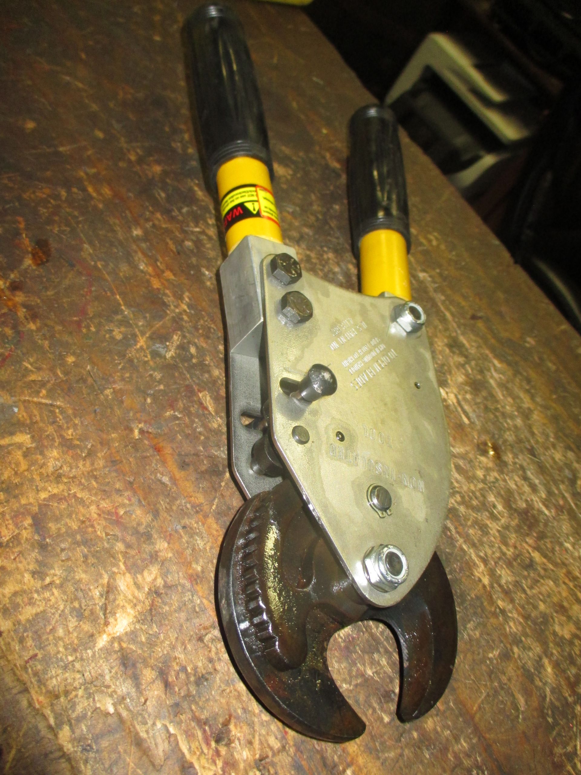 A pair of pliers with yellow handles is sitting on a wooden table