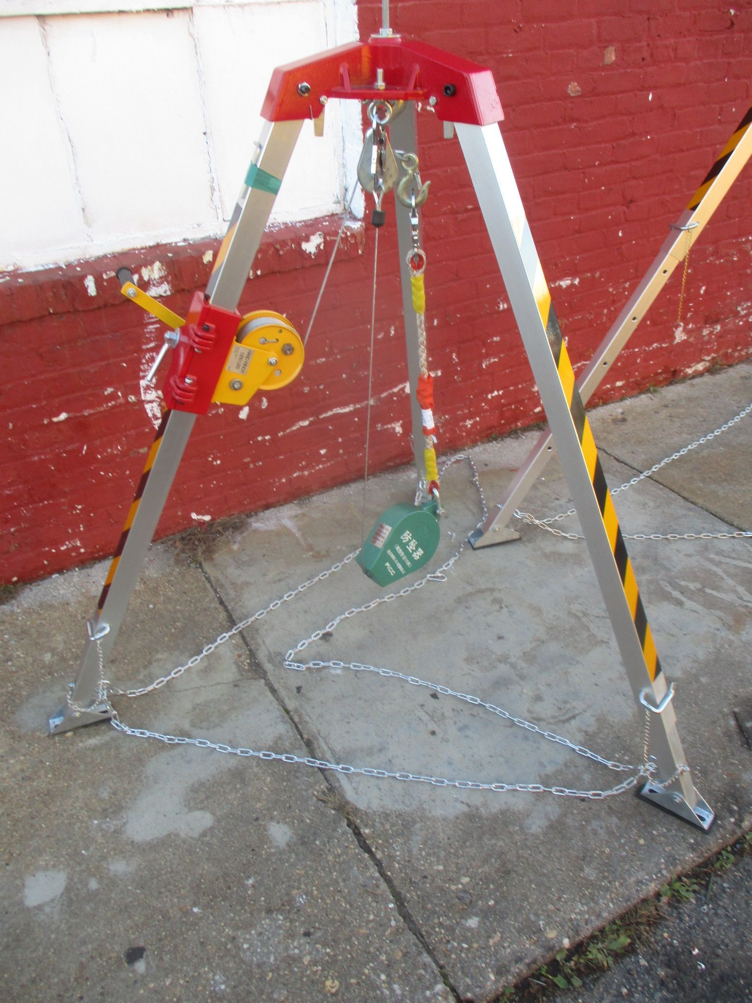 A tripod is sitting on a sidewalk in front of a red brick wall
