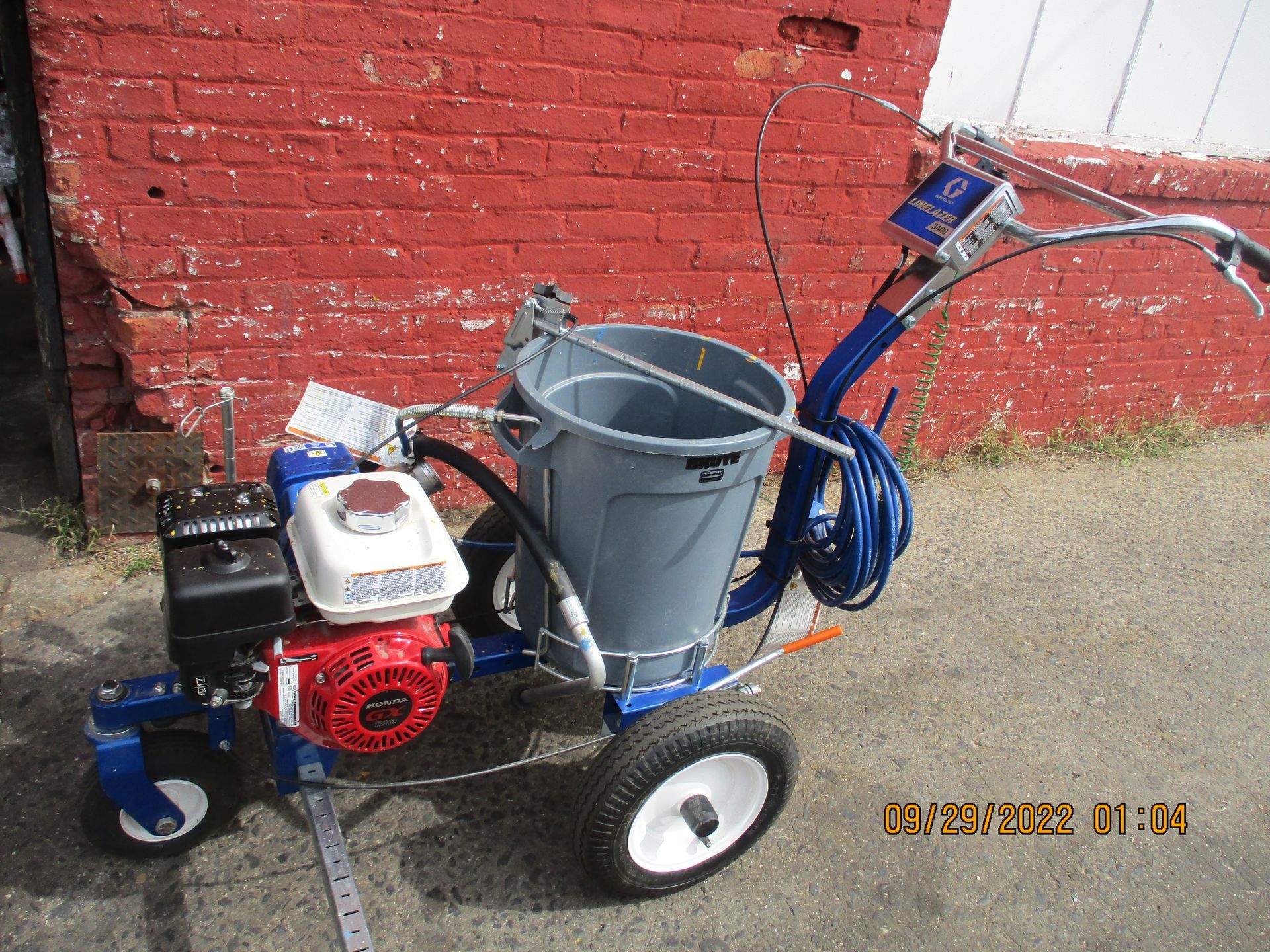 A machine with a bucket attached to it is sitting in front of a red brick wall.