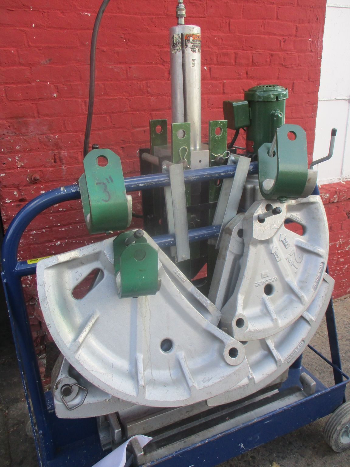 A machine is sitting on a cart in front of a red brick wall