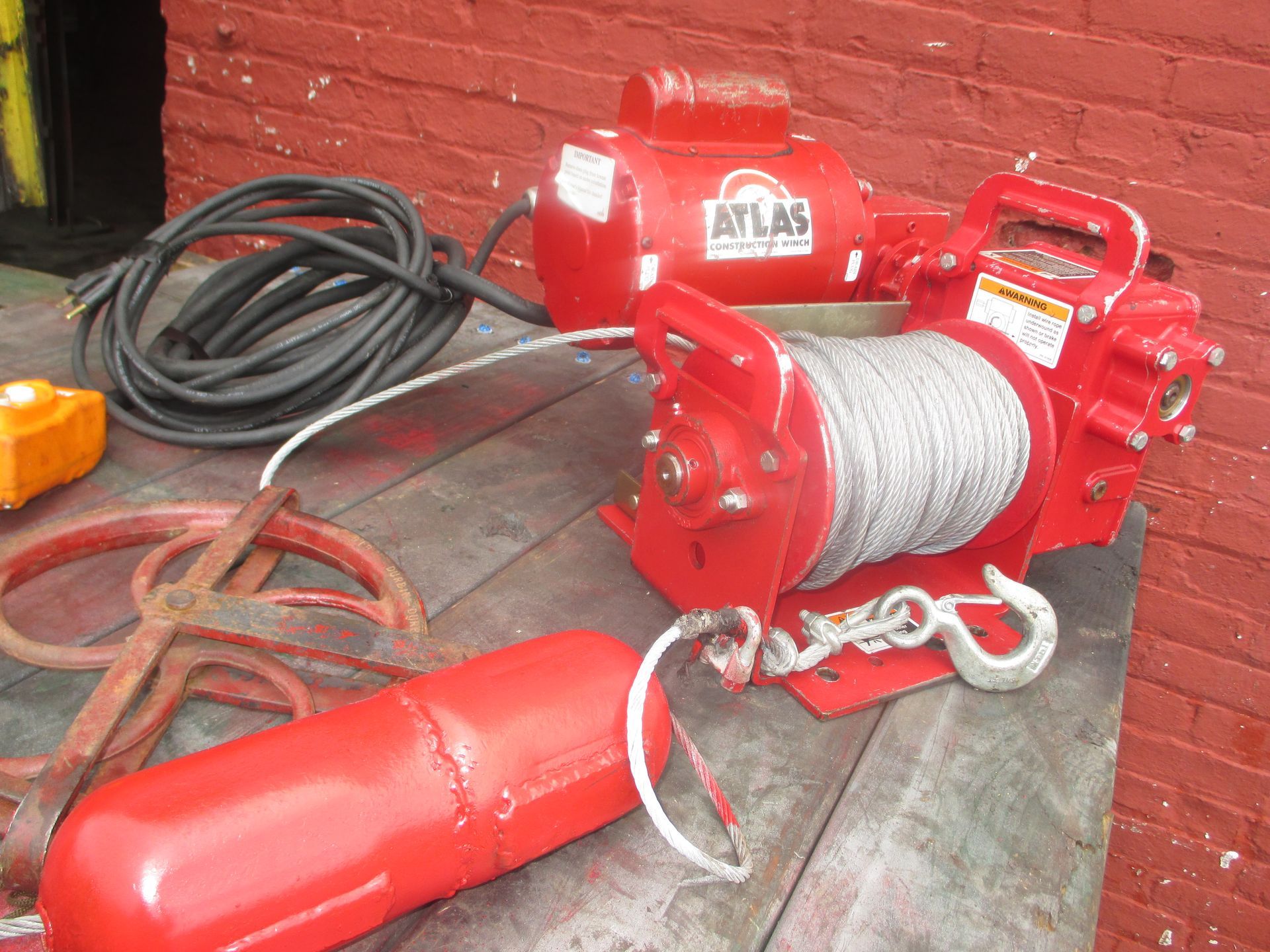 A red atlas winch is sitting on a wooden table