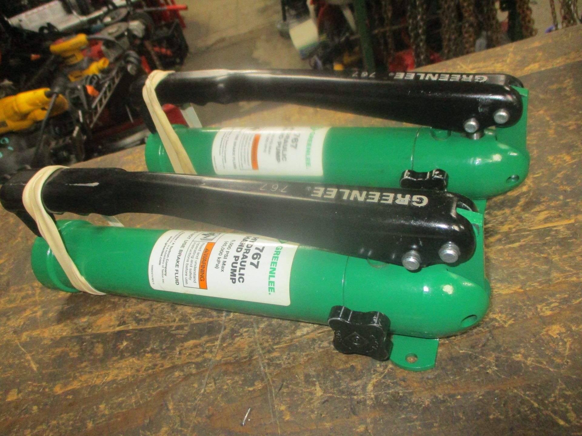 Two green greenlee hand pumps are sitting on a table