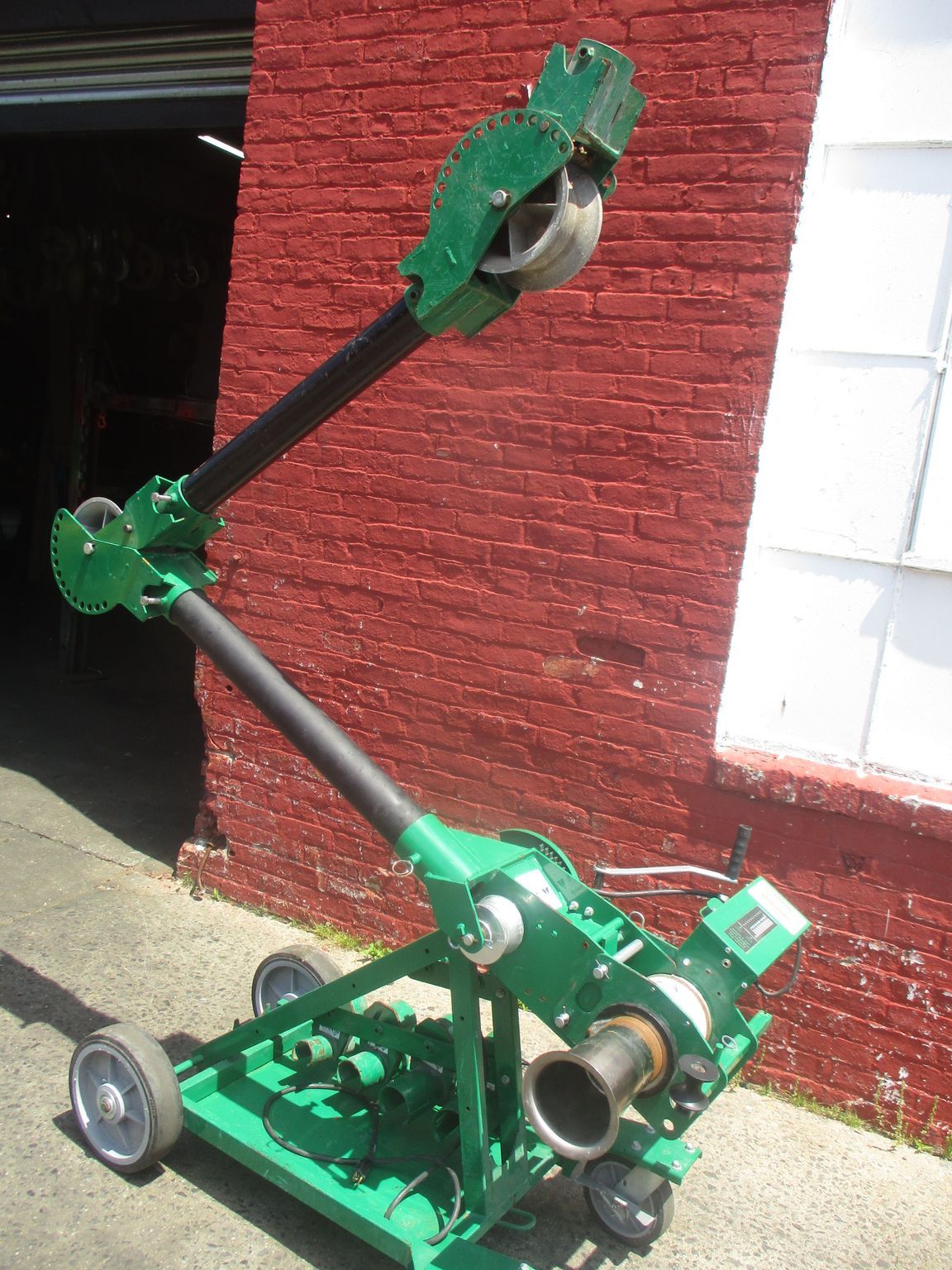 A green machine is parked in front of a red brick building