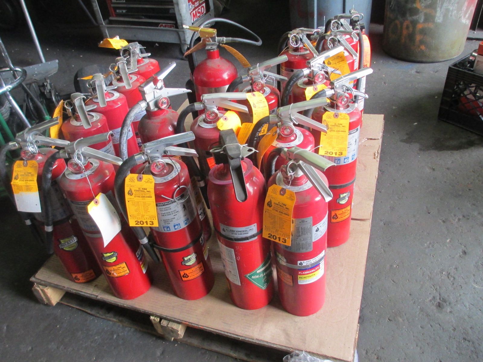A bunch of red fire extinguishers on a wooden pallet