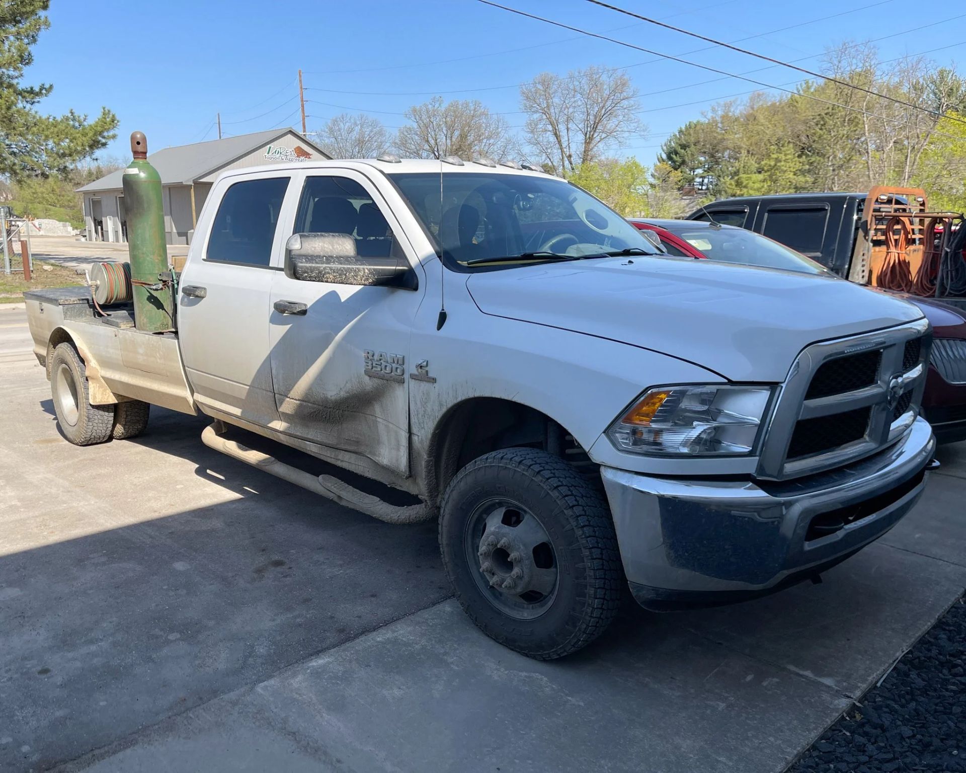 White flatbed pickup truck with front-end damage parked outdoors on a sunny driveway