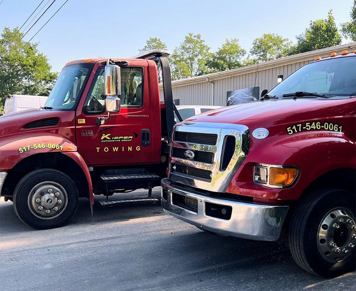 Two red tow trucks parked side by side in a lot
