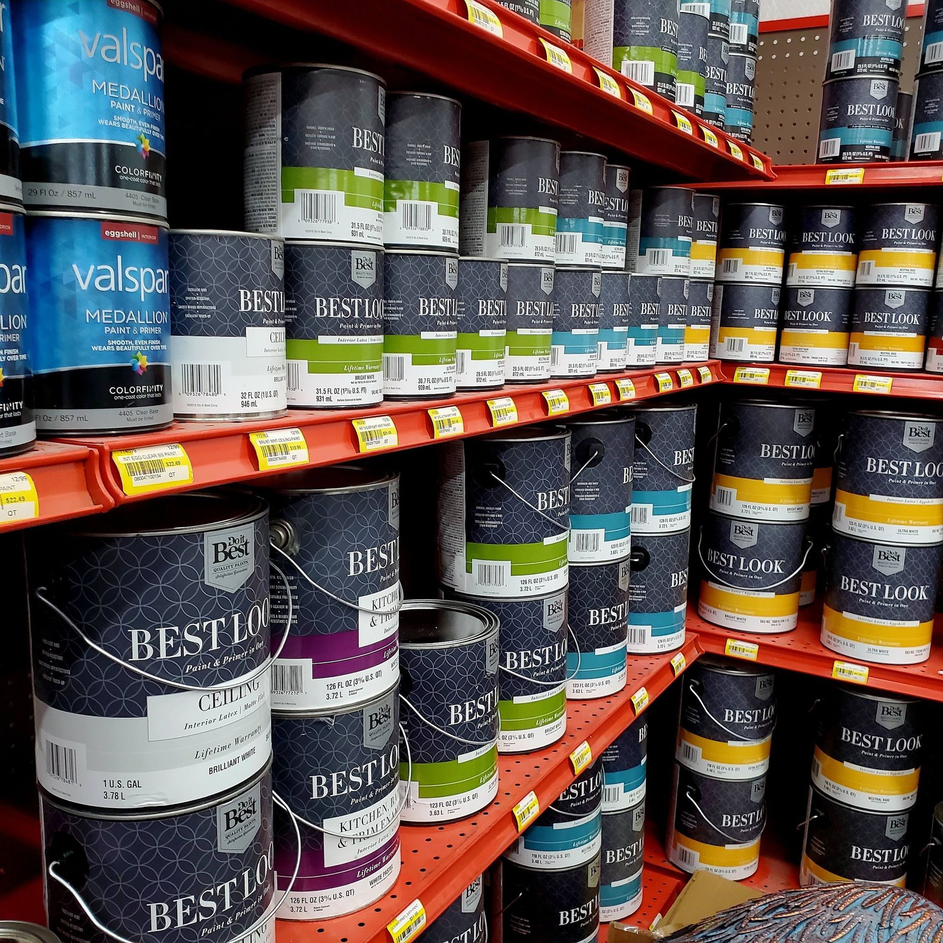 Shelves filled with various cans of Best Look and Valspar paint in a retail store.