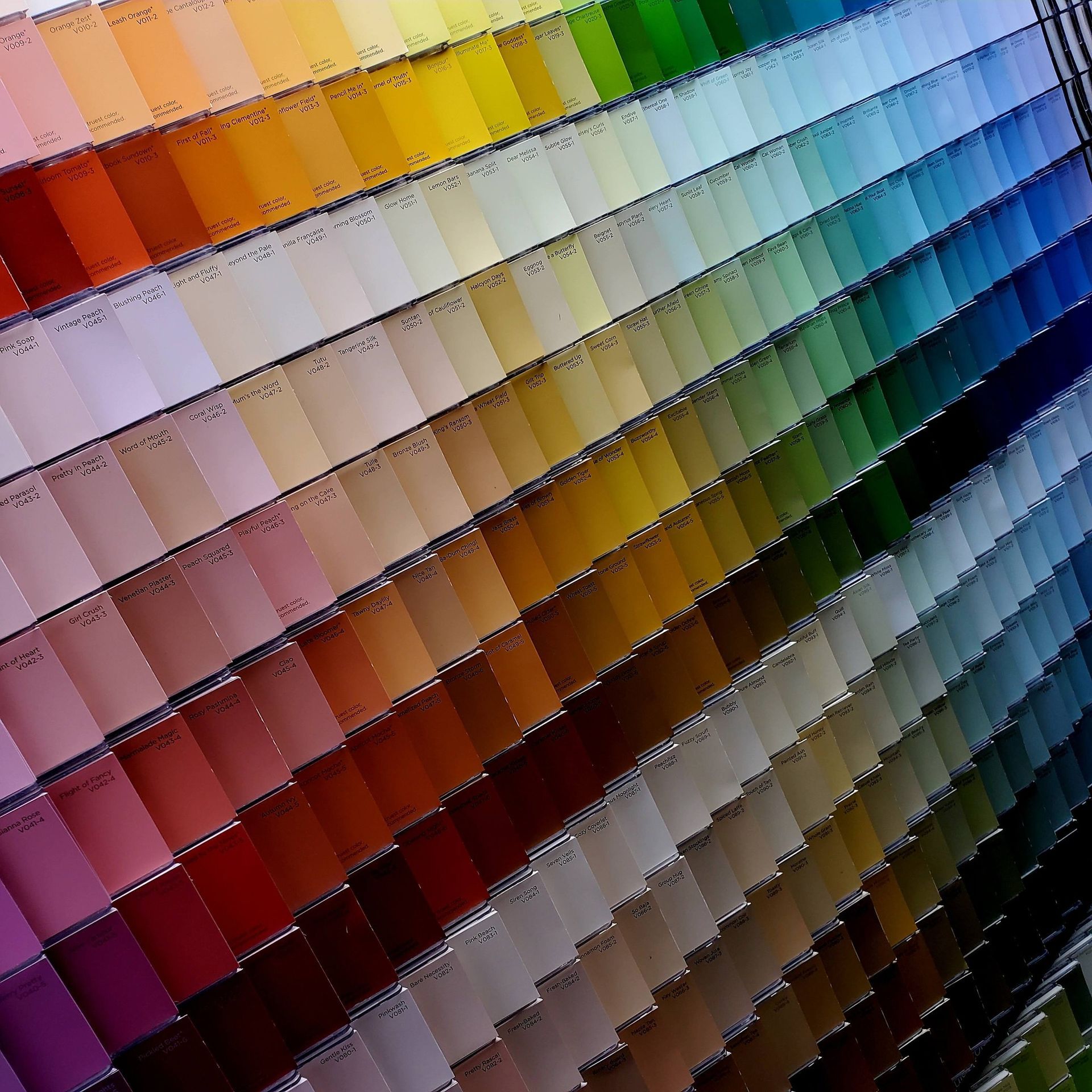 A wide array of paint color sample cards arranged in a gradient, spanning the full color spectrum.