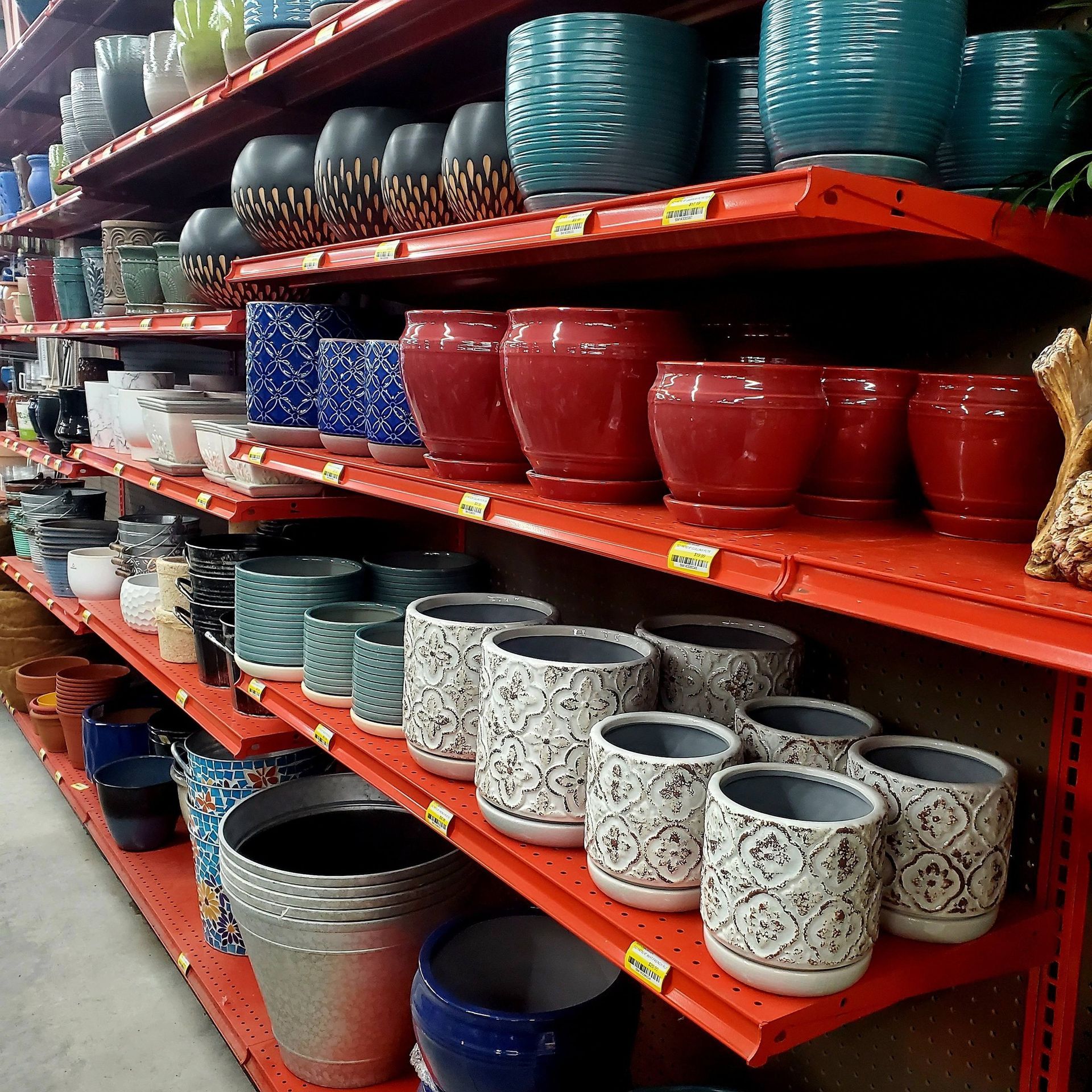 Store shelves stocked with a variety of colorful ceramic and metal flower pots in different sizes and patterns.