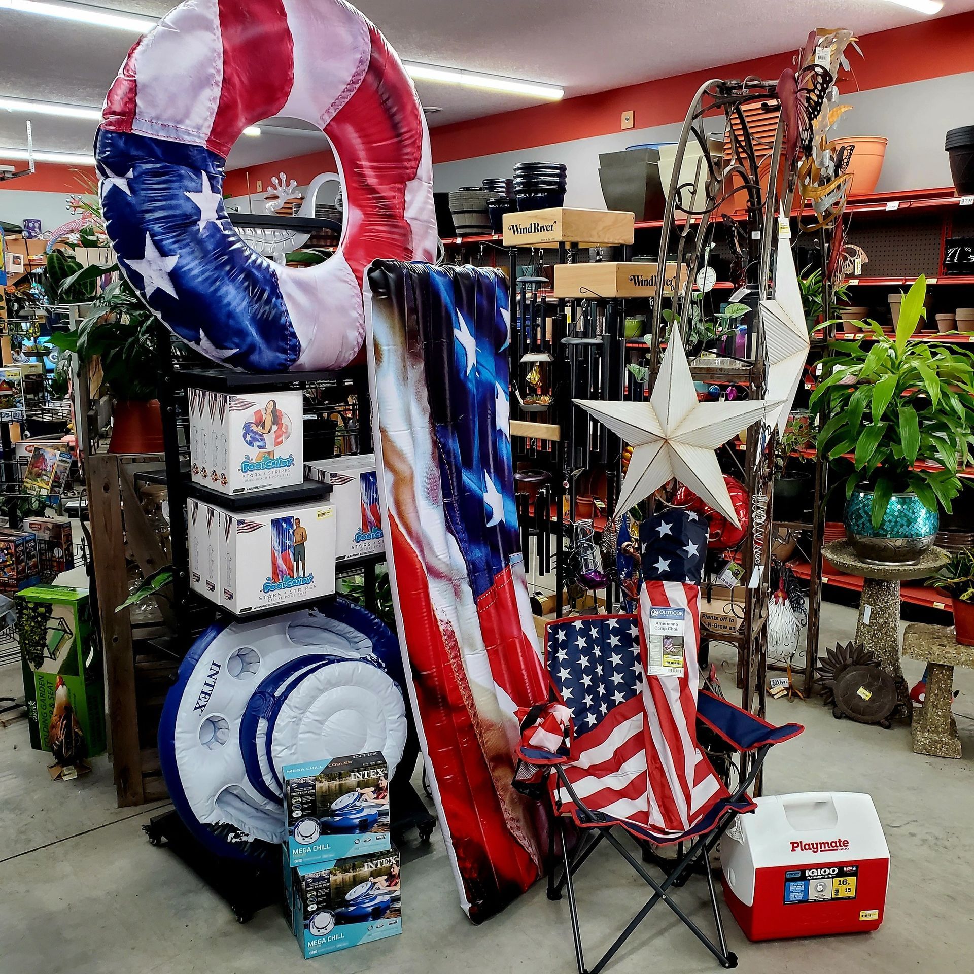 A store display of red, white, and blue patriotic items, including pool floats, a folding chair, and a cooler.