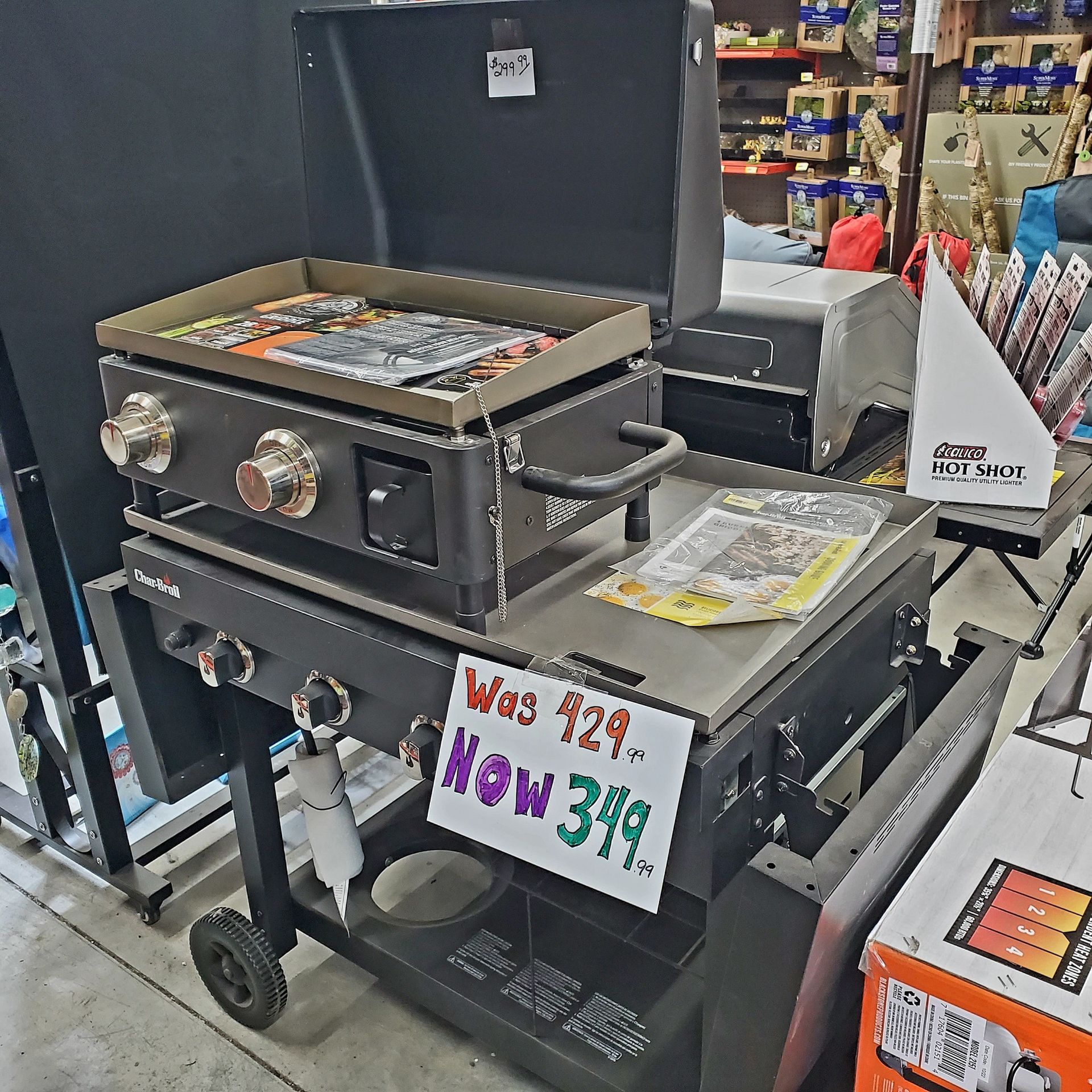 A black outdoor griddle on a cart with a sign showing a price reduced from 429 to 349.
